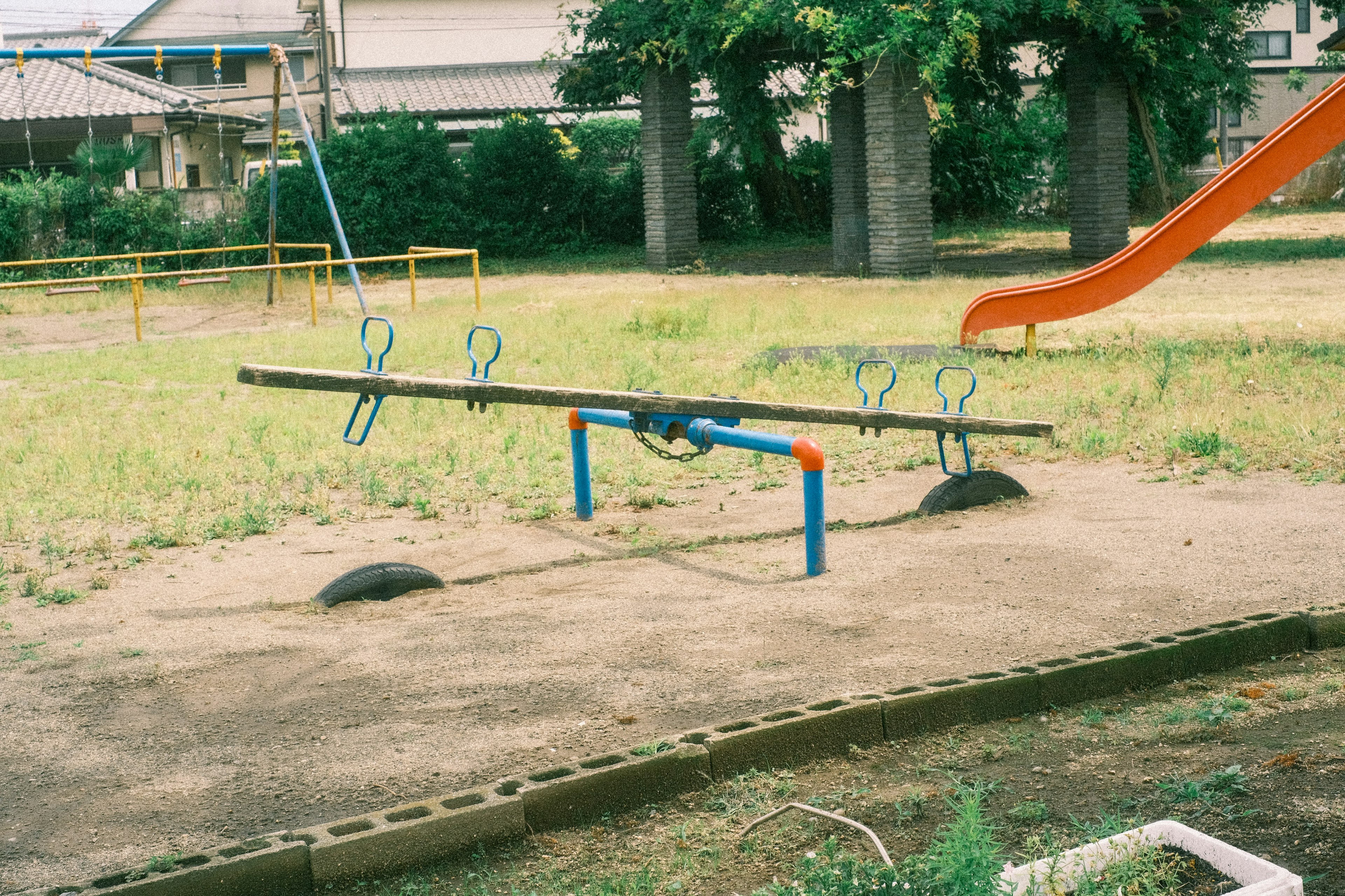 Playground scene with a seesaw and swings in a grassy area