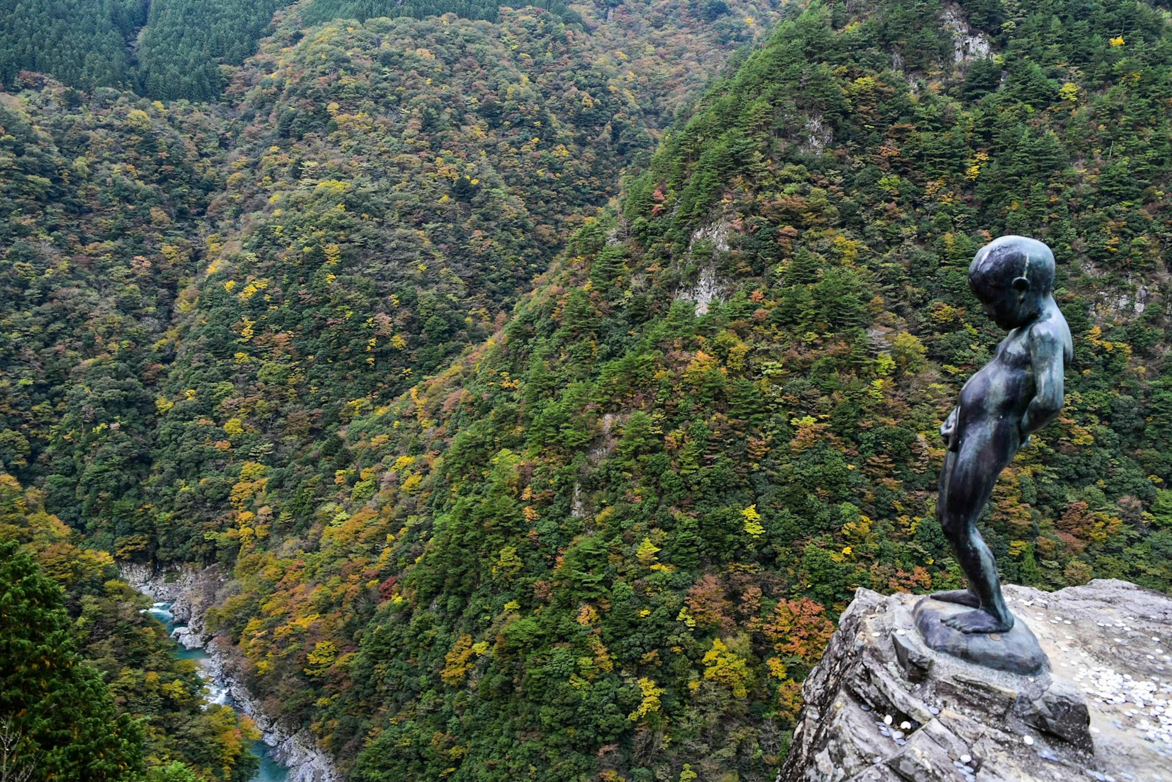 美しい山の景色を背景にした小さな青銅の像