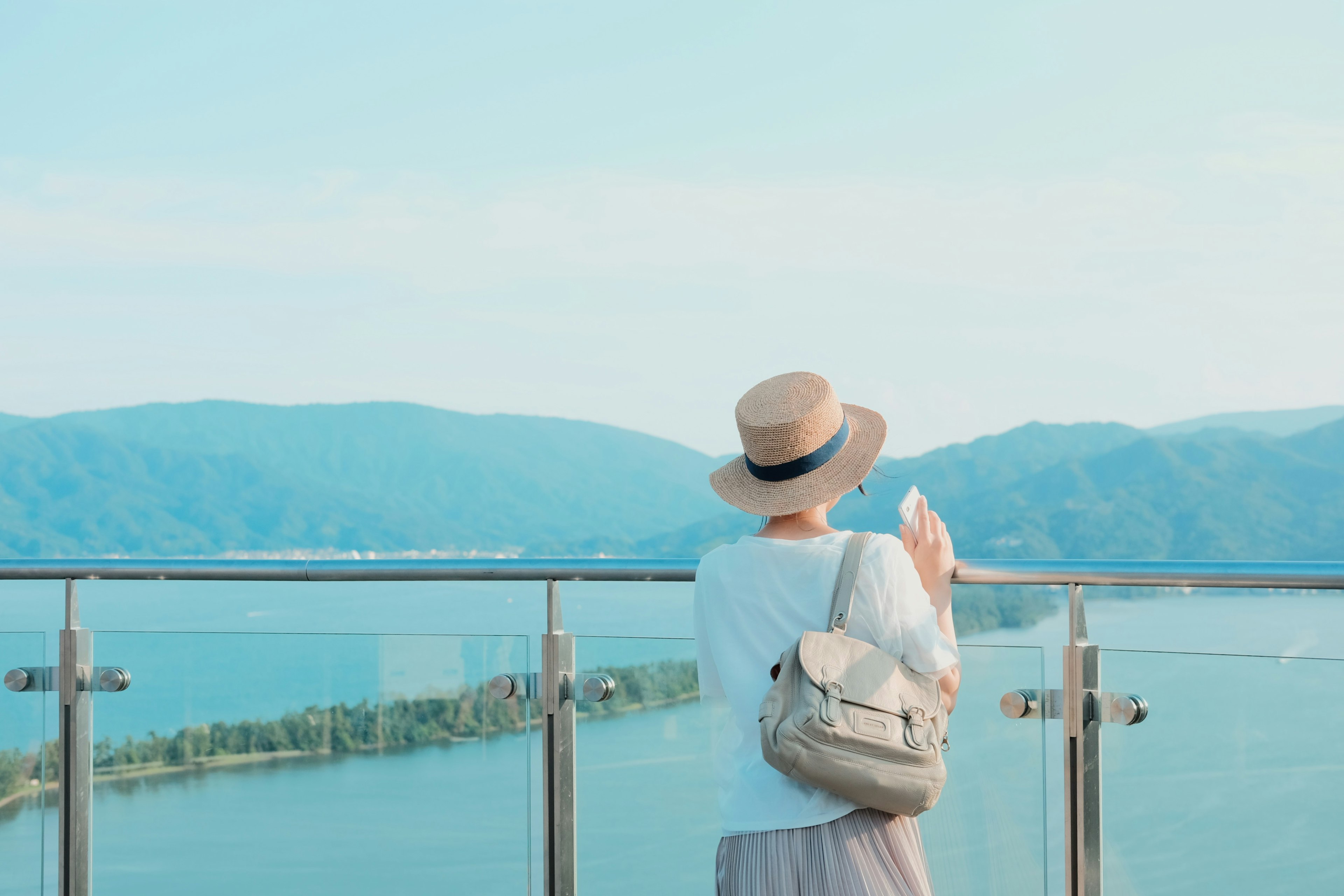 Une femme portant un chapeau et un sac à dos regardant une vue panoramique de la mer