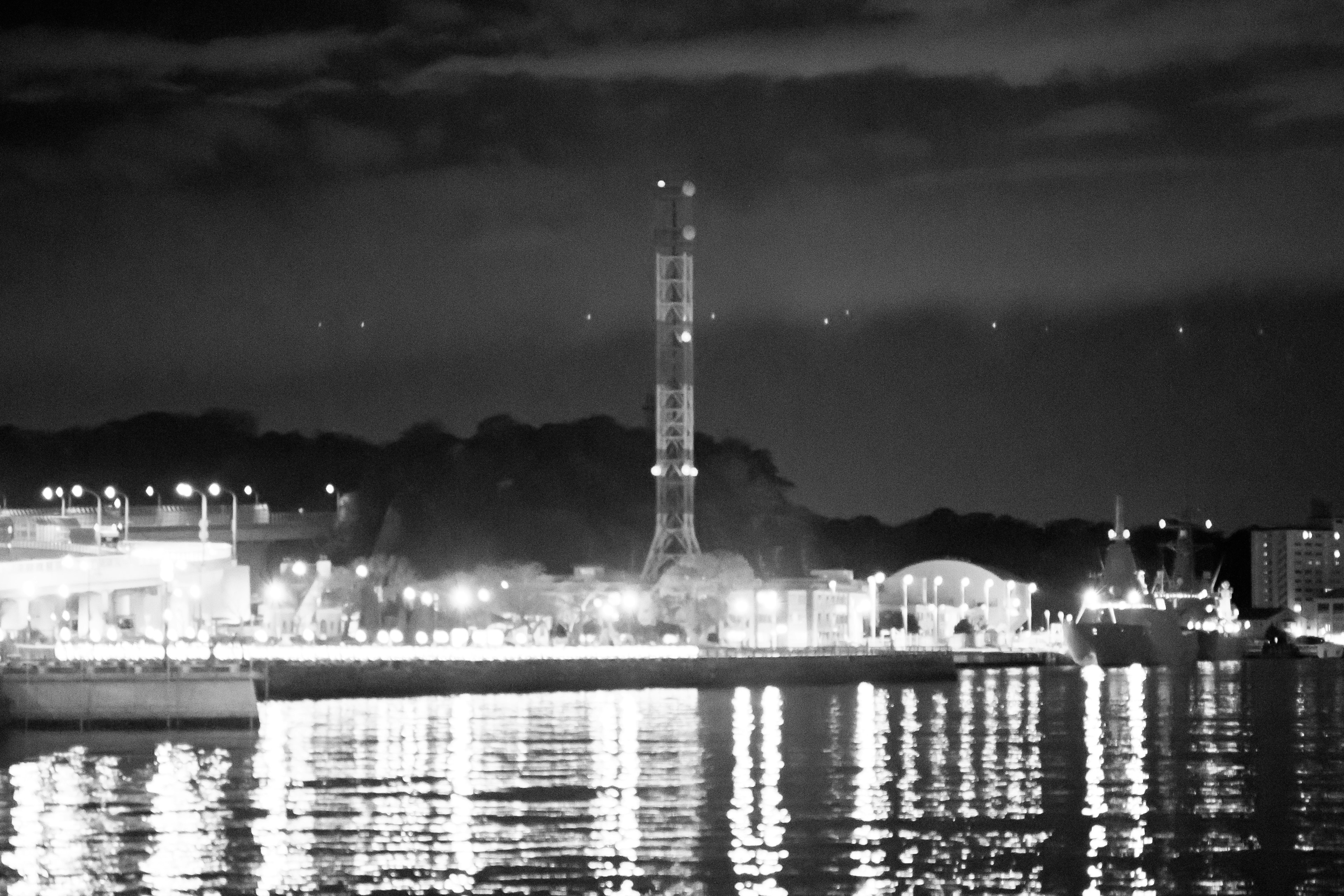 Scena costiera notturna con una bella torre illuminata e riflessi in bianco e nero