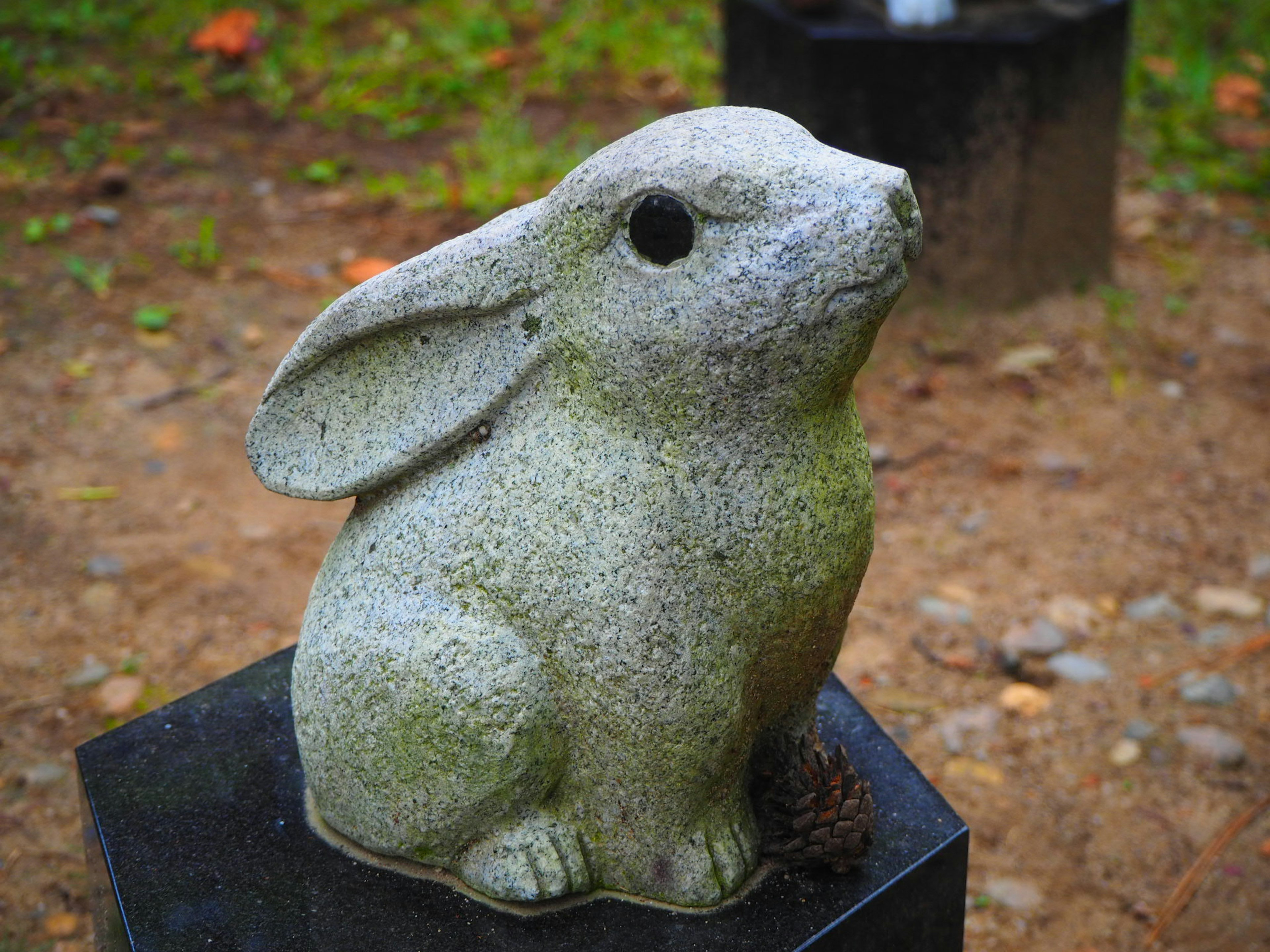 Stone rabbit sculpture sitting on a pedestal outdoors