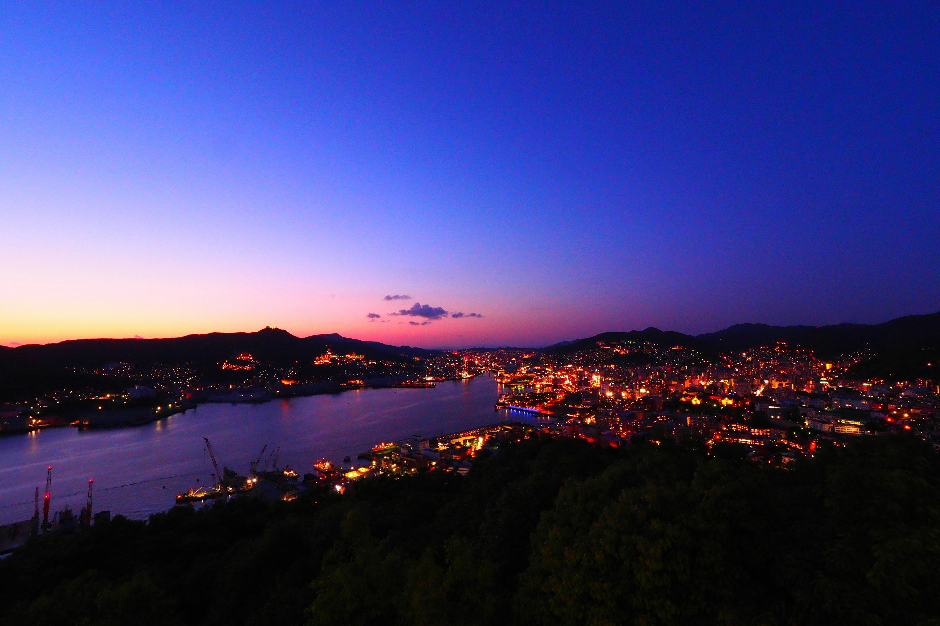 Hermosa vista nocturna de una ciudad portuaria con cielo azul-púrpura