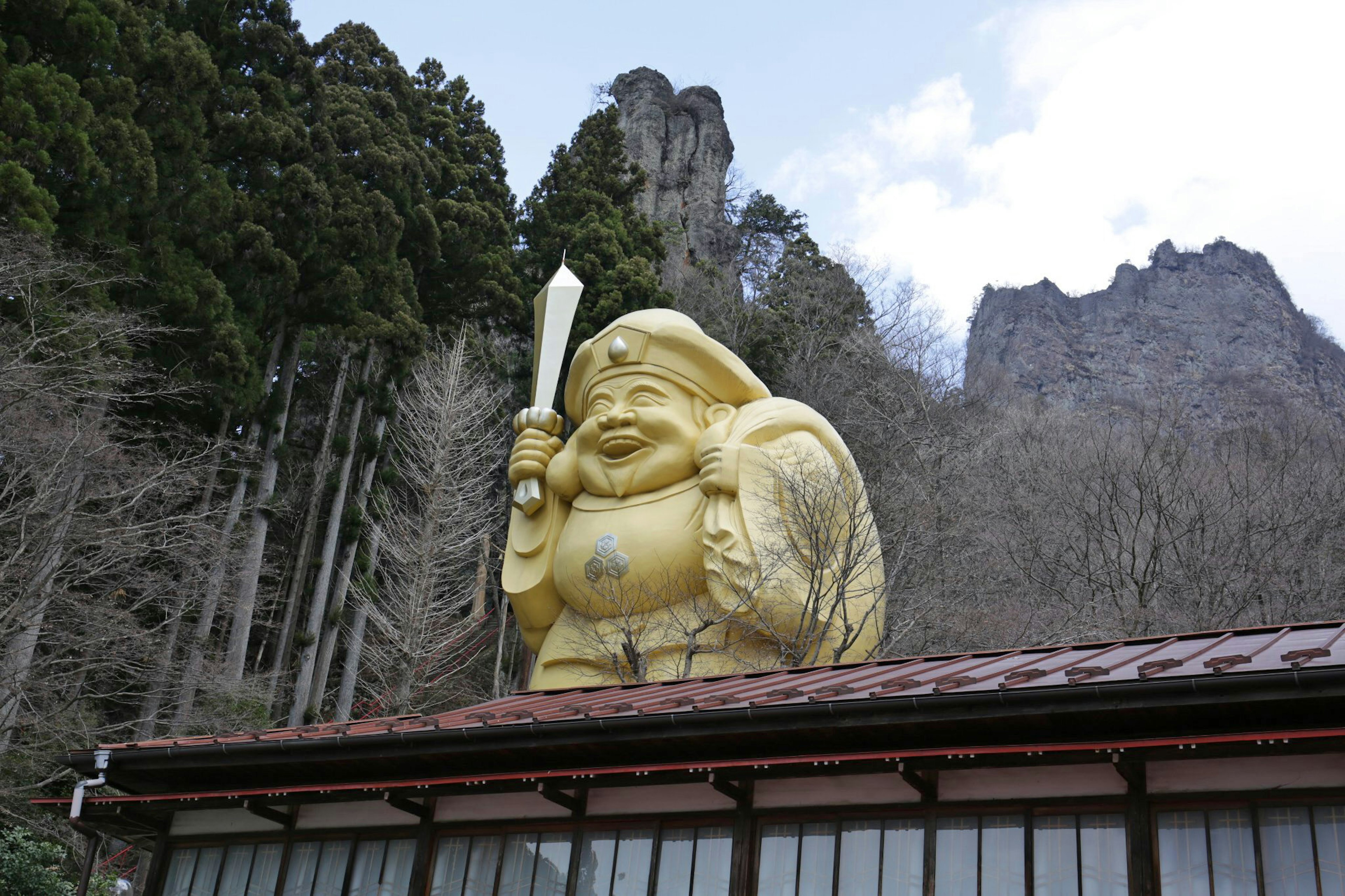 A large golden statue stands against a mountainous backdrop