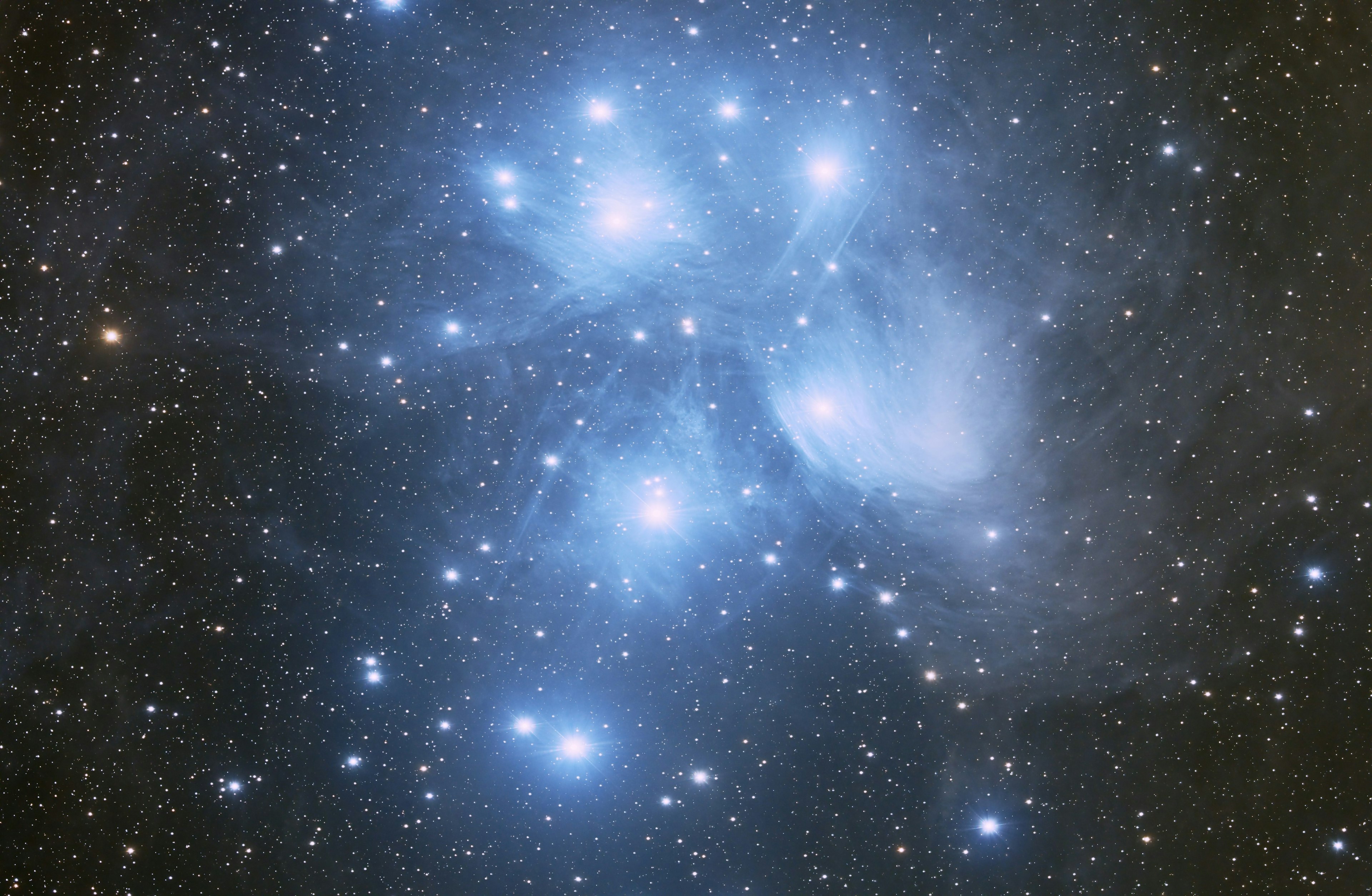 Image of a star cluster with blue stars and wispy gas