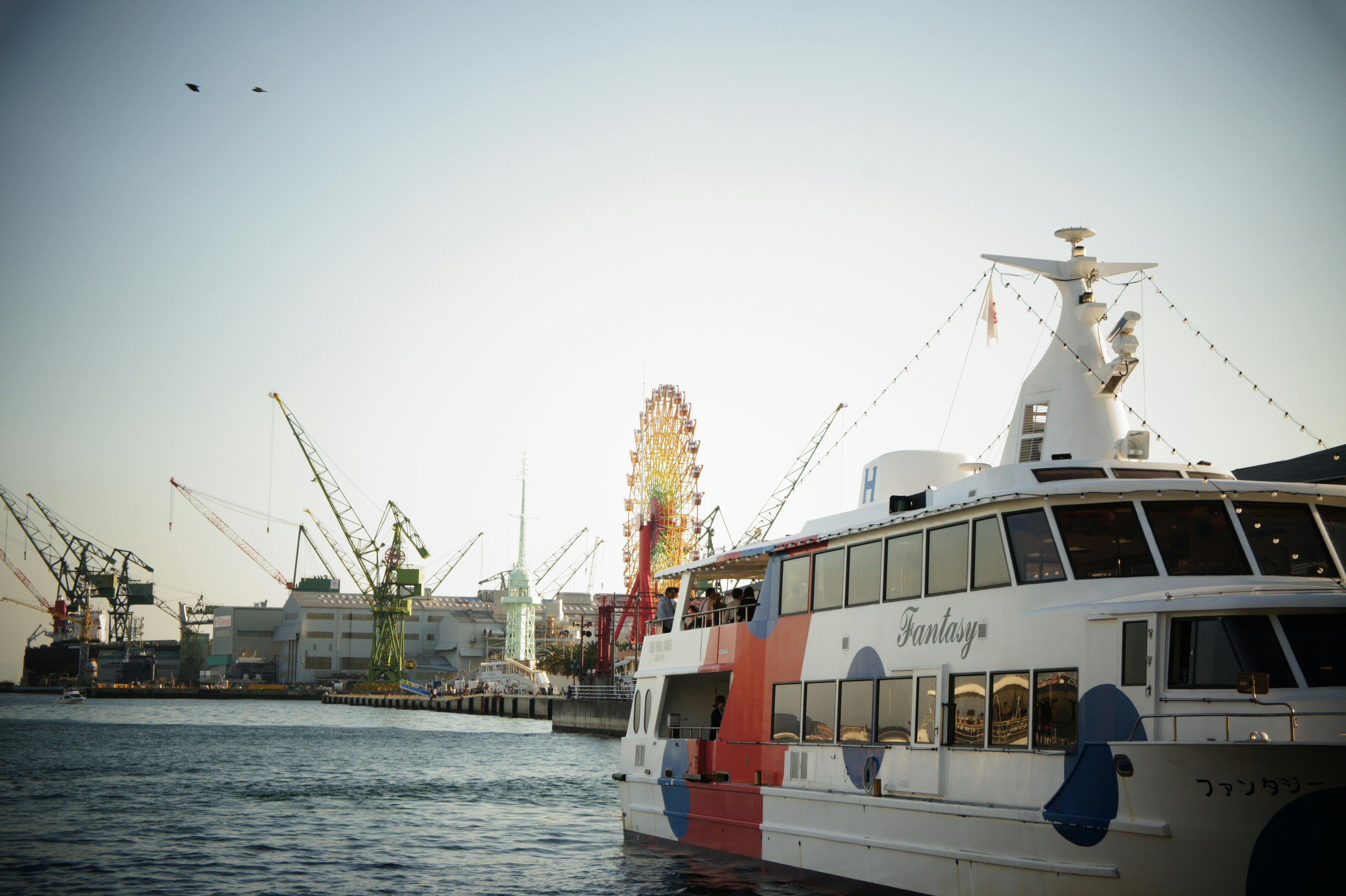 Ein Boot im Hafen mit einem Riesenrad im Hintergrund