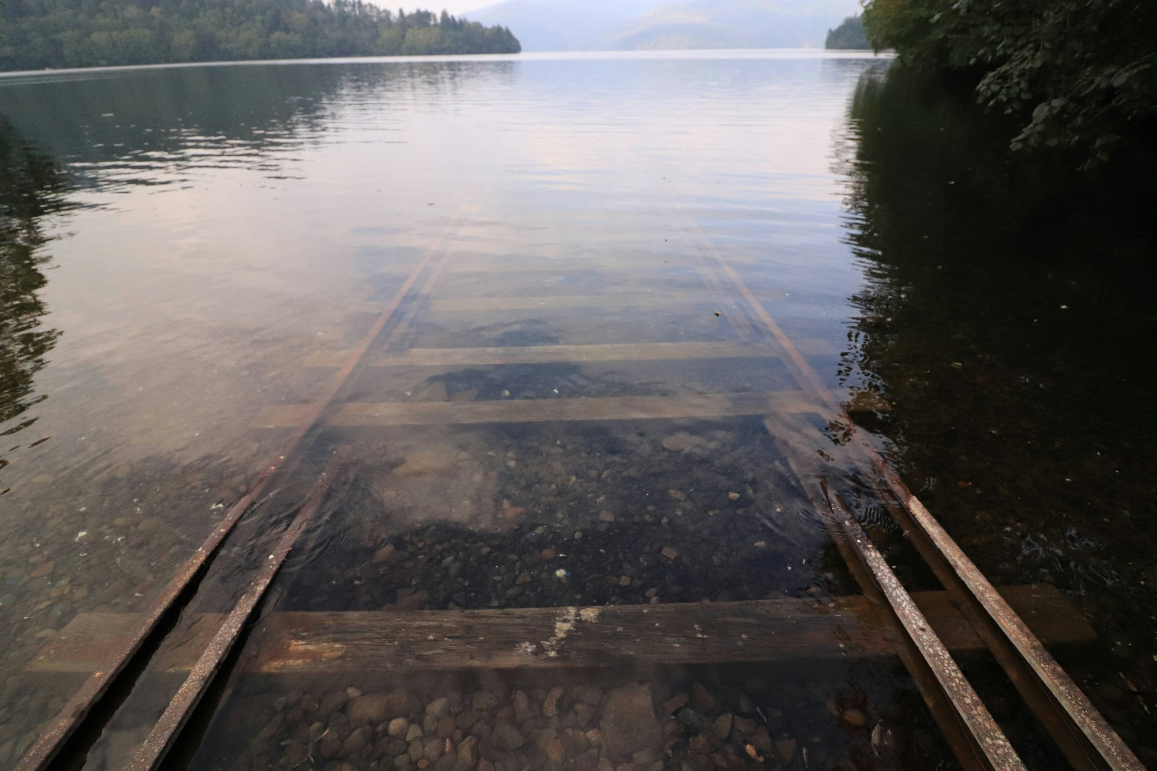 Muelle de madera que se extiende hacia un lago tranquilo reflejando el cielo