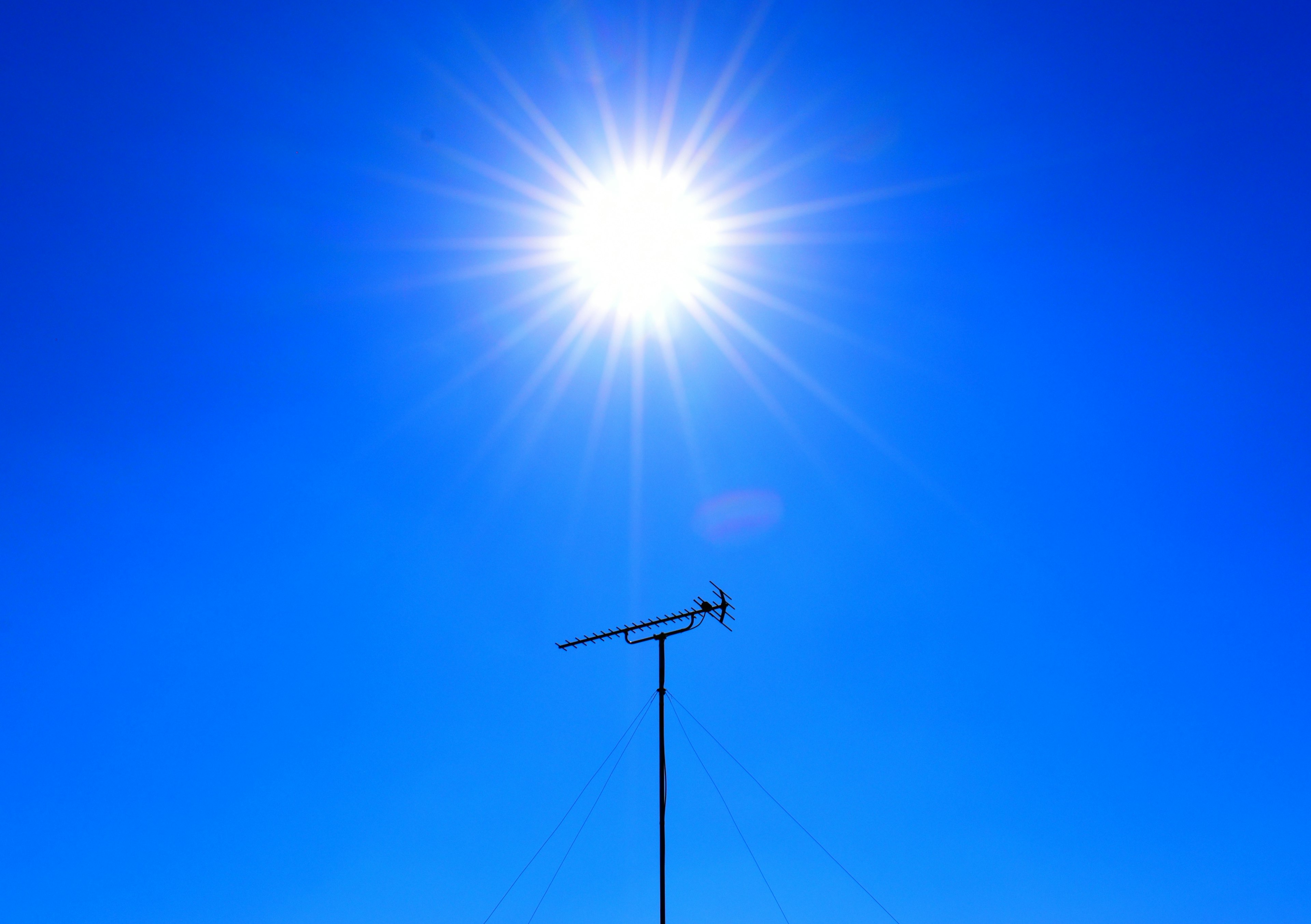 Sol brillante en un cielo azul claro con una antena abajo