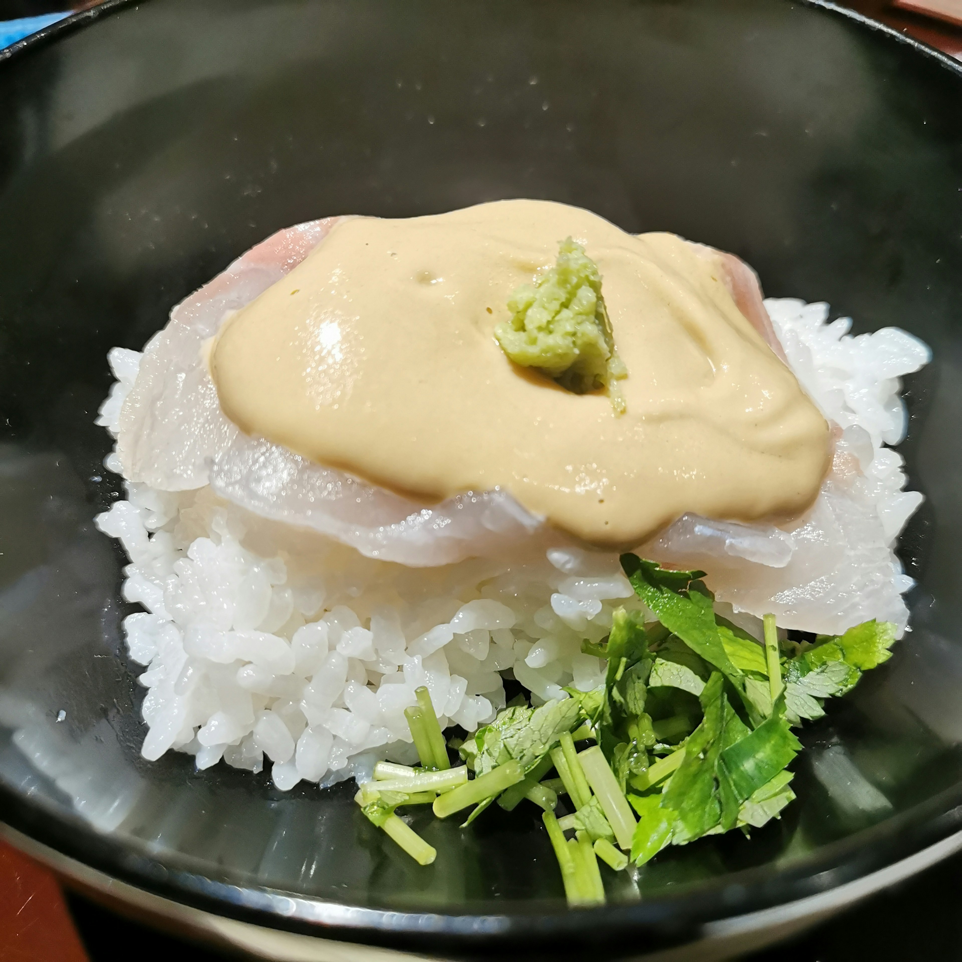 Dish featuring fresh sashimi topped with wasabi on a bed of white rice