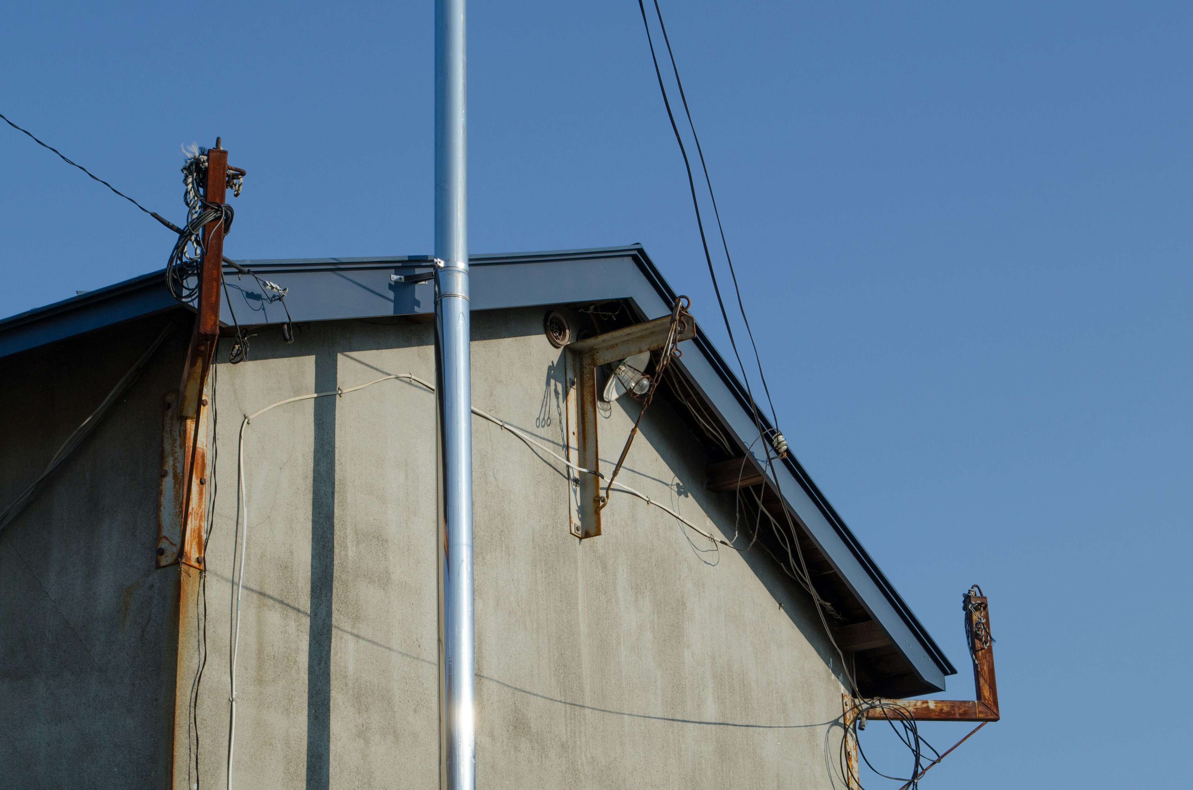 Metal wiring and pole at the corner of a building roof