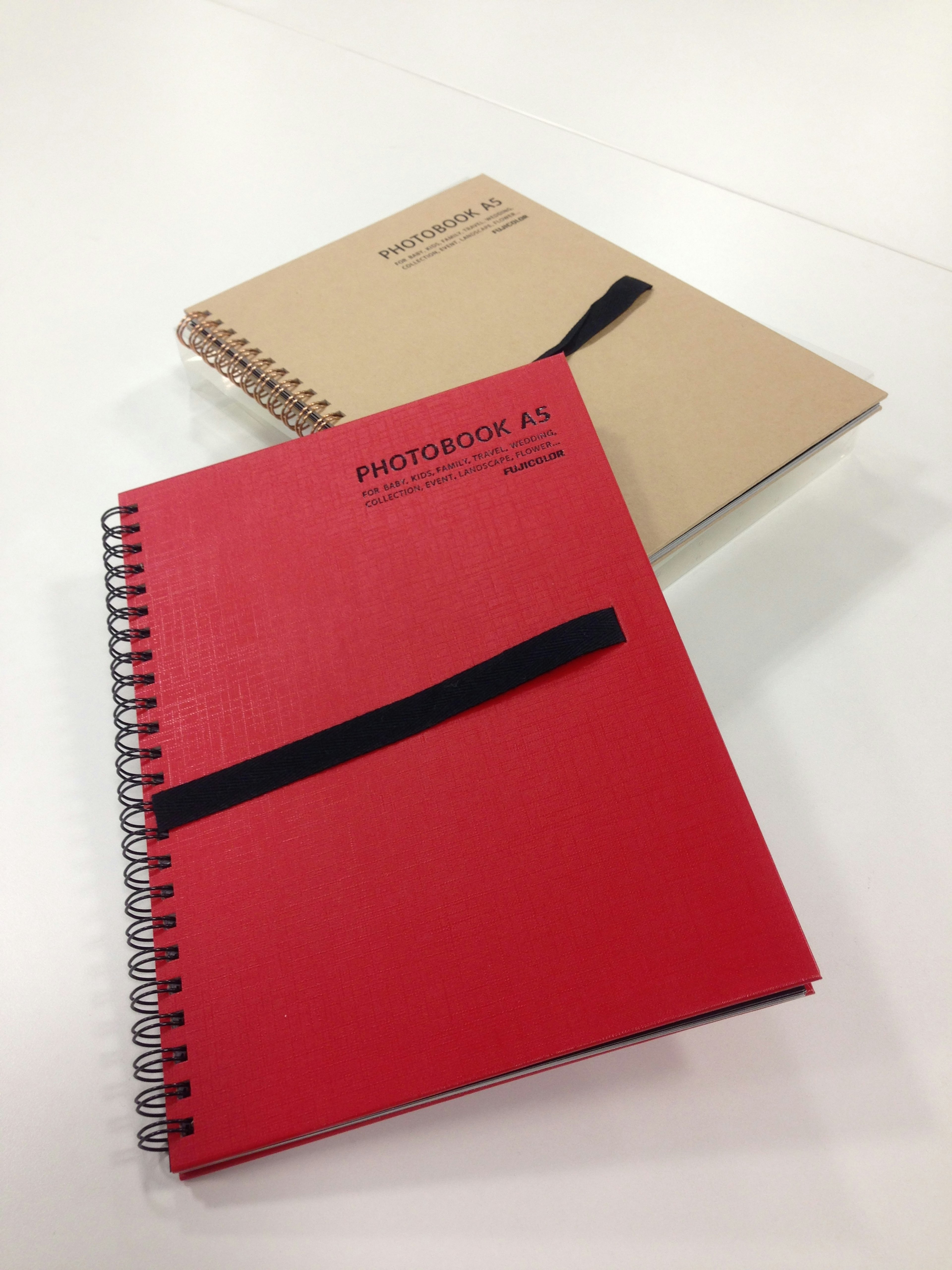 A red spiral notebook and a beige notebook are placed together