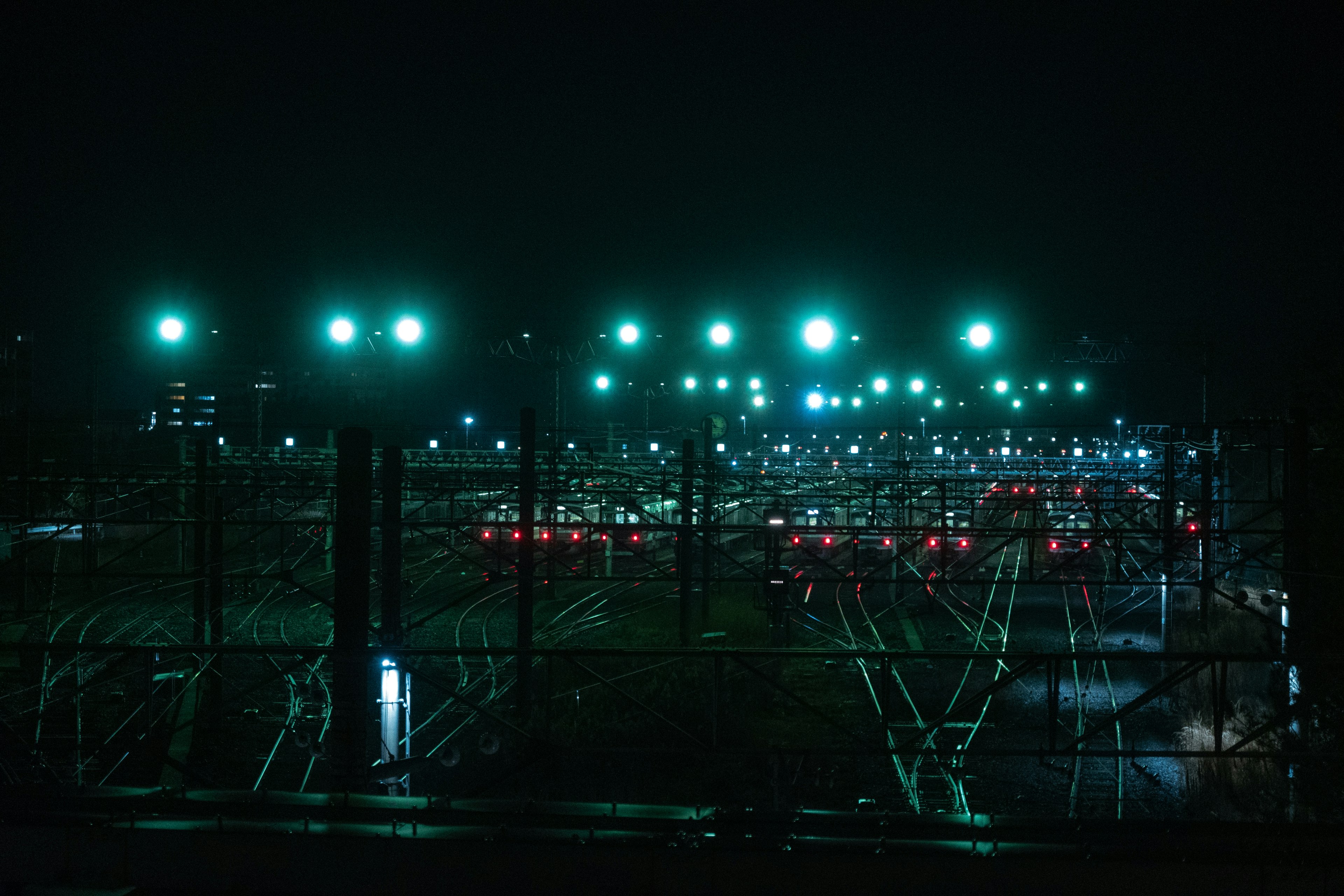 Vista nocturna de un patio ferroviario con luces verdes iluminando las vías