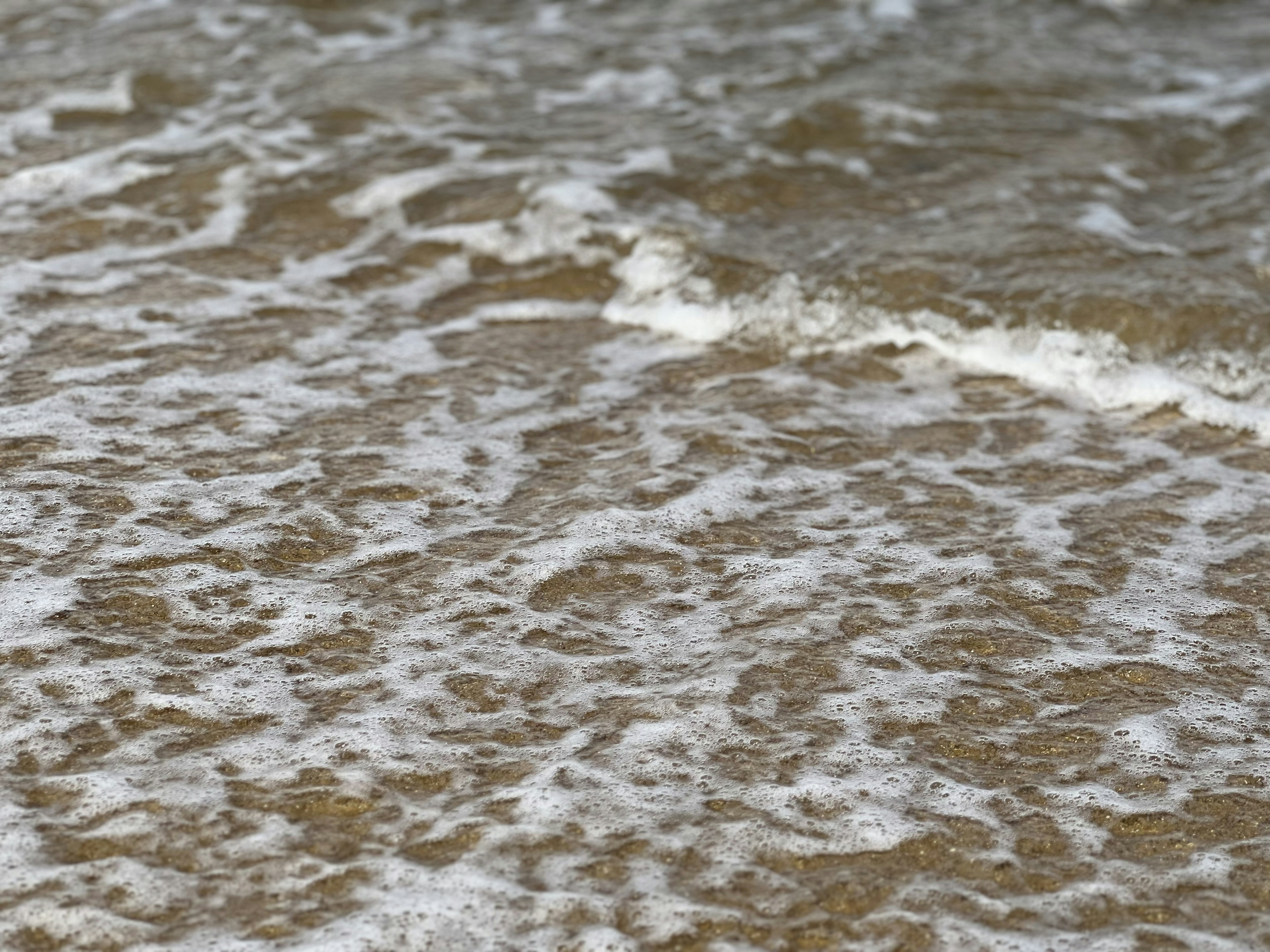 Superficie del océano con olas rompiendo en una playa de arena