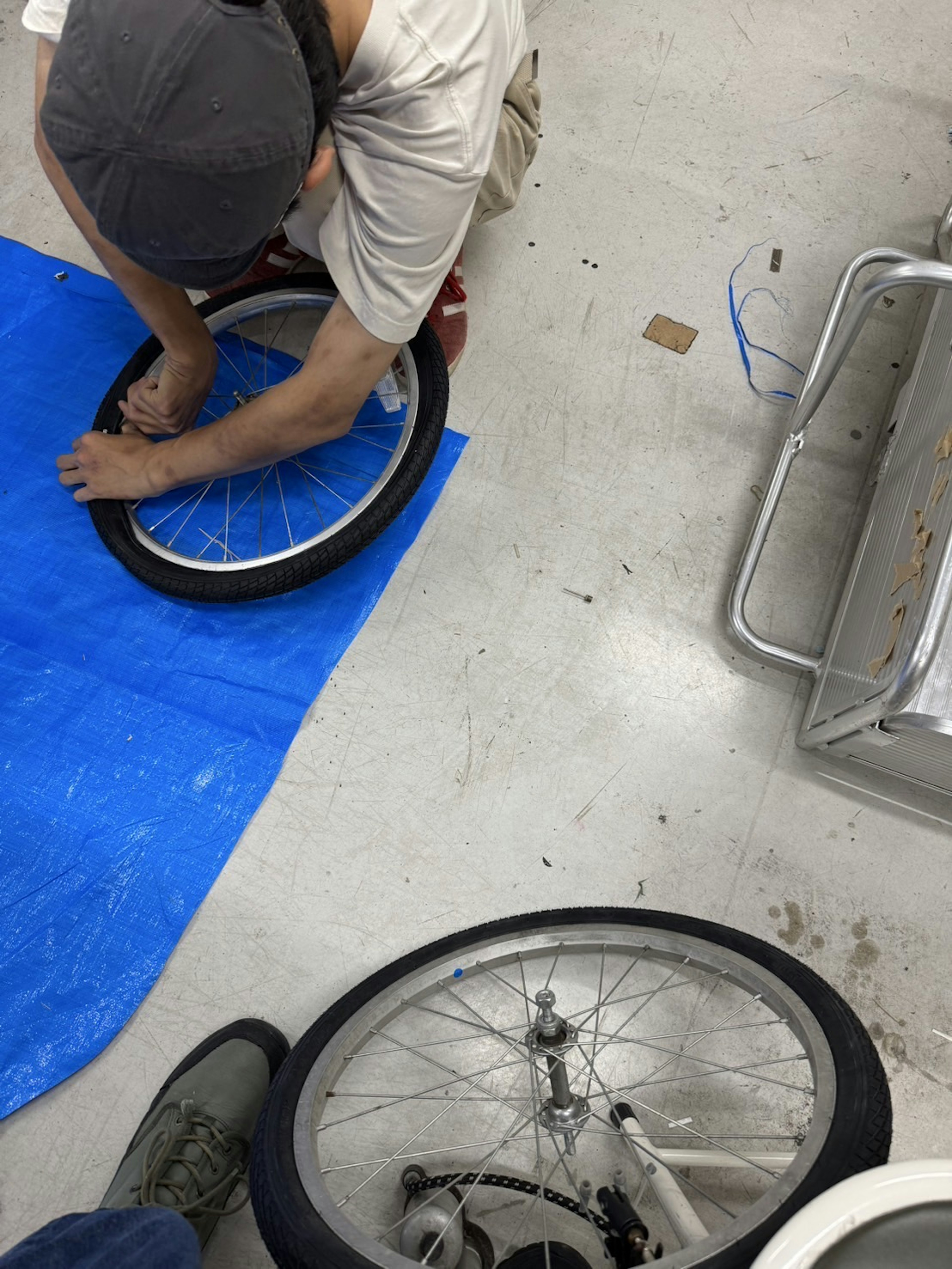 Persona reparando un neumático de bicicleta sobre una lona azul