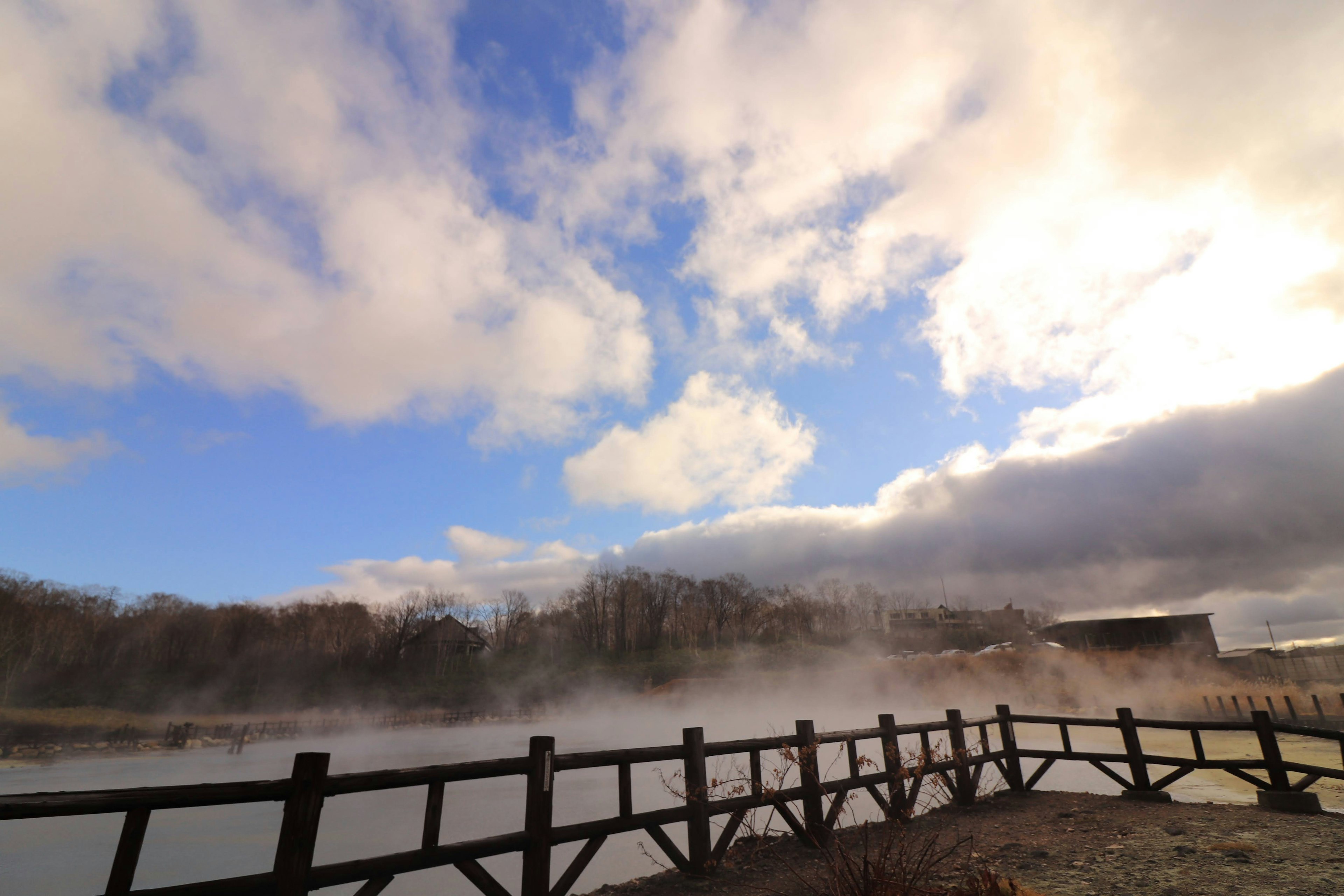 Landscape featuring a misty pond and a wooden bridge