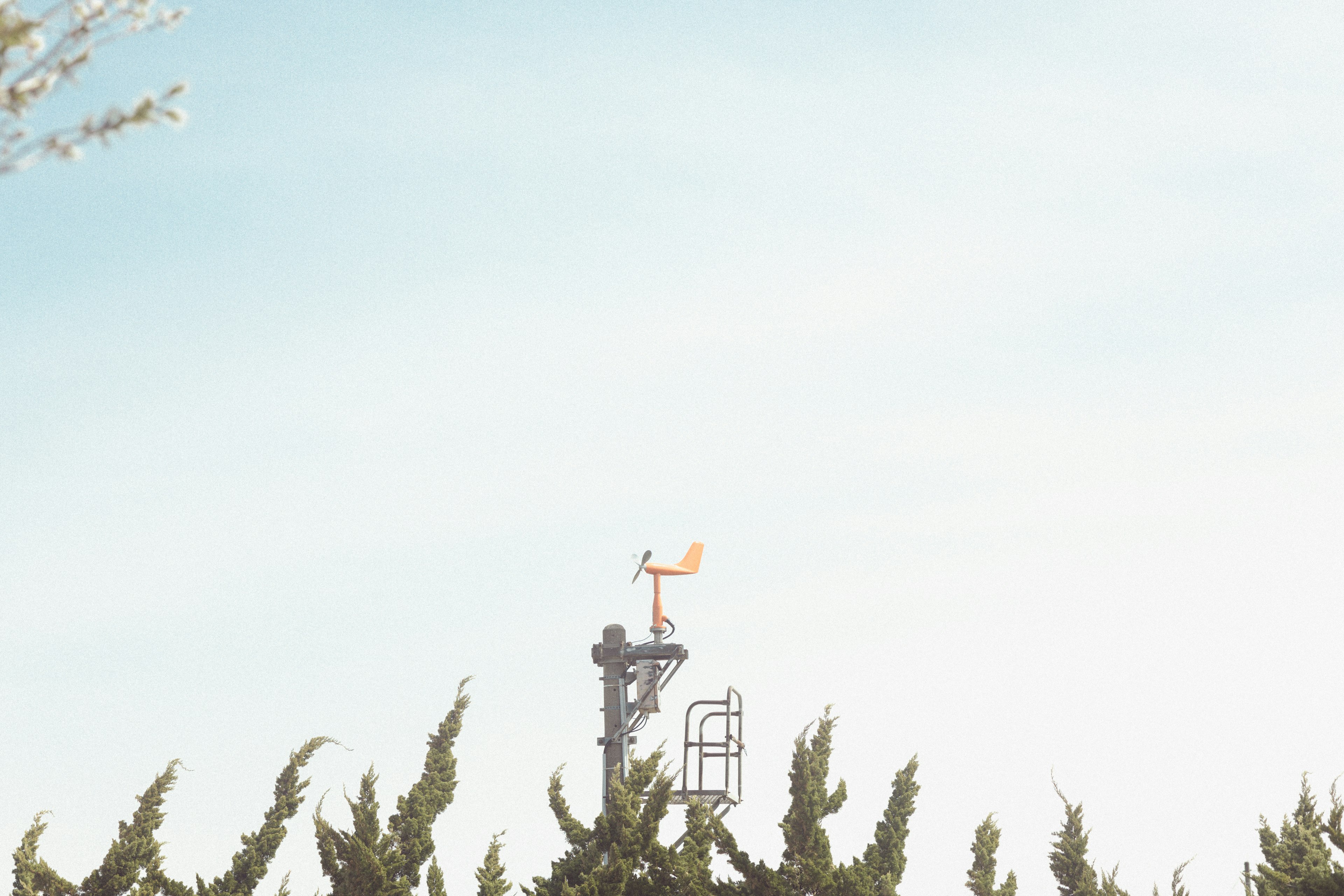 Communication tower with wind vane and anemometer against a blue sky