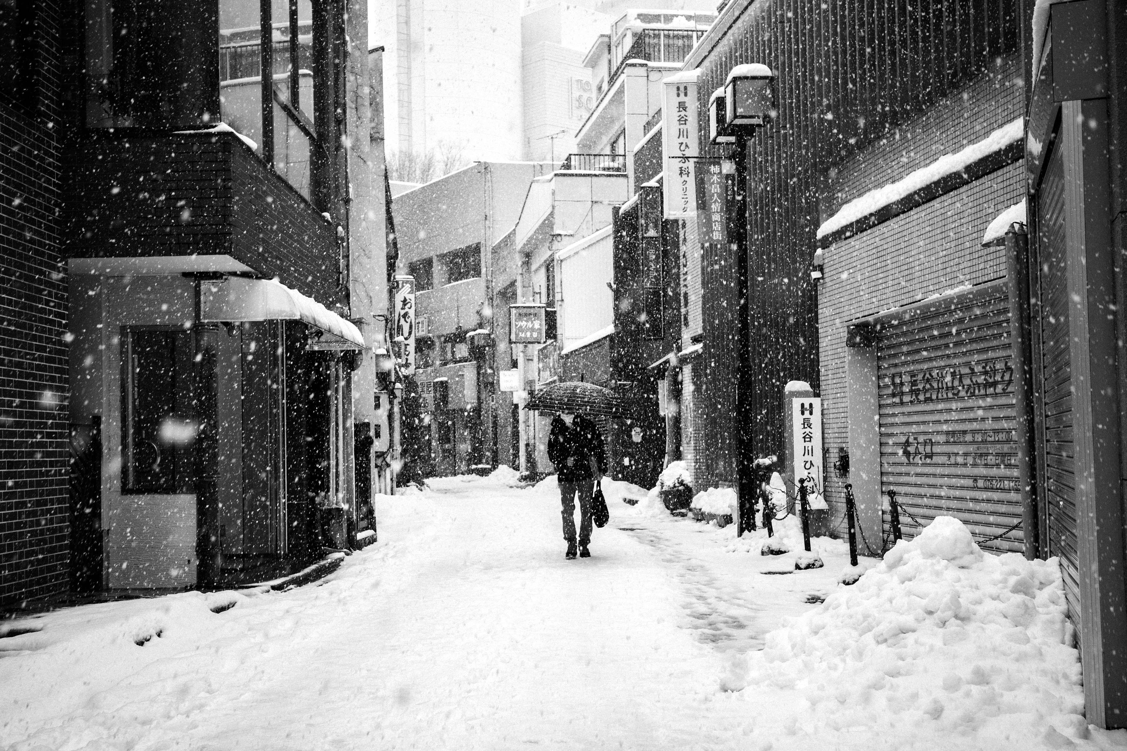 Une personne marchant avec un parapluie dans une ruelle enneigée