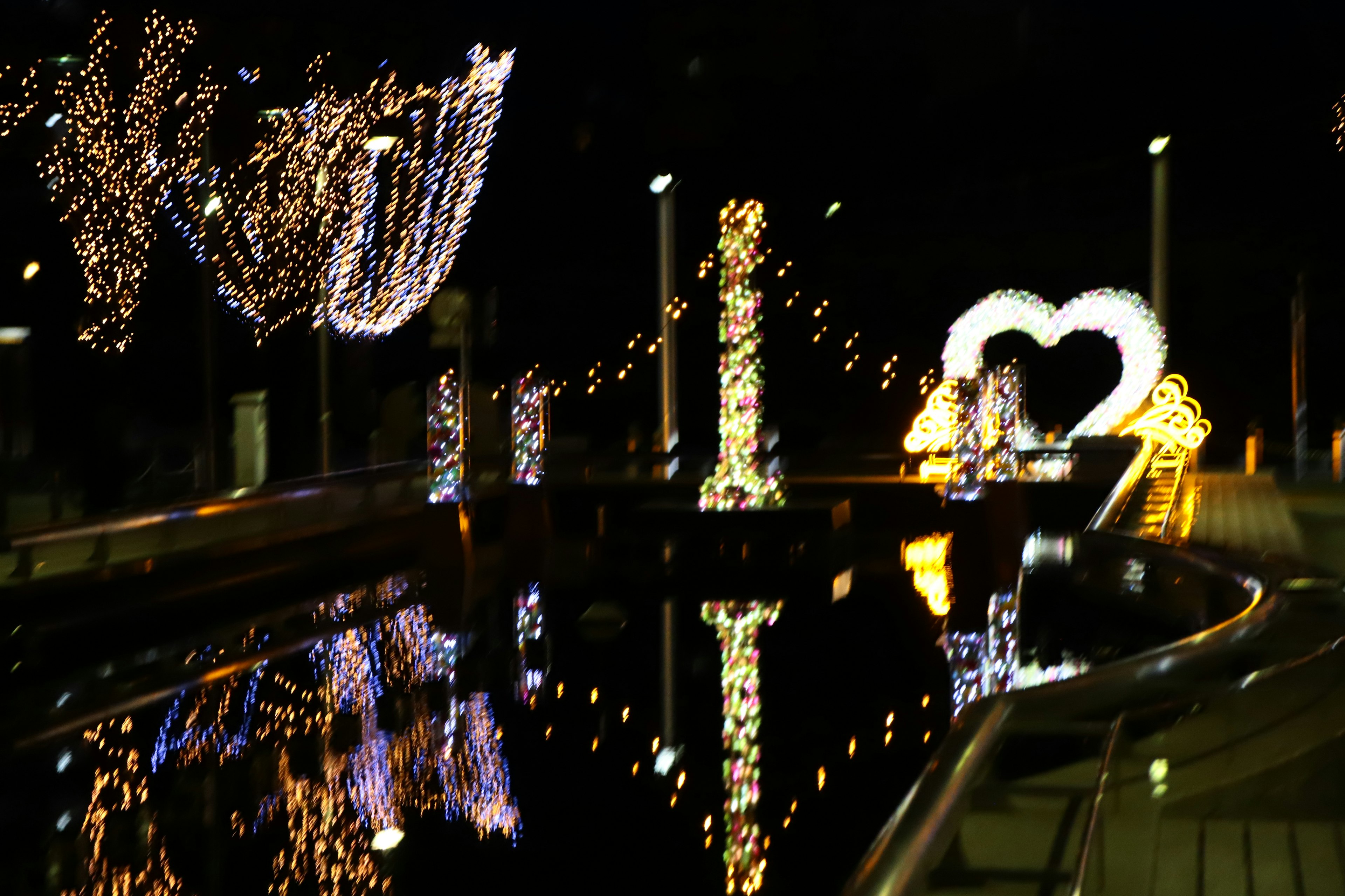 Cœur illuminé et décorations se reflétant sur une rivière la nuit