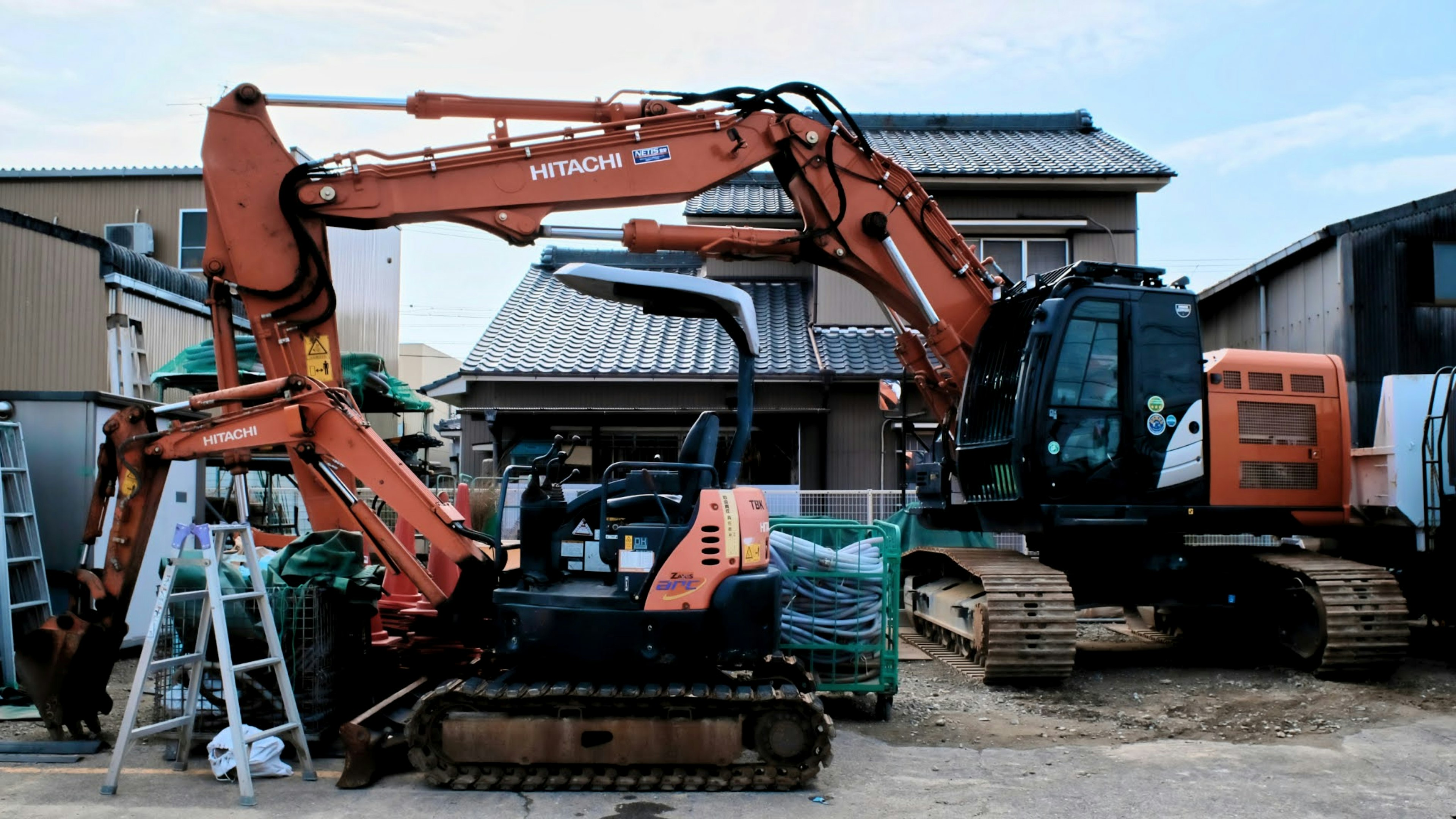 Xe xúc màu cam và máy màu đen tại công trường