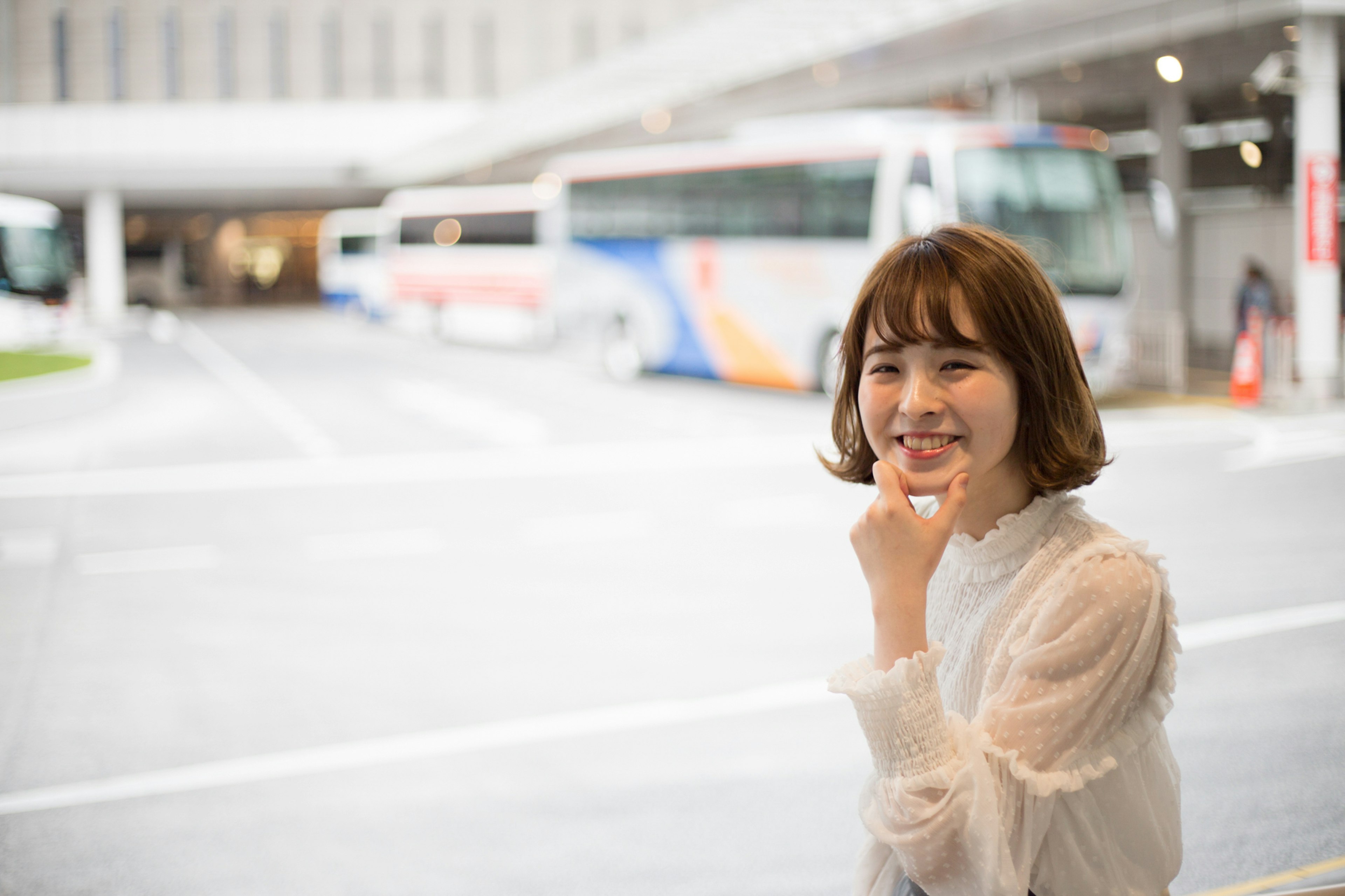 Smiling woman touching her mouth at a bus stop