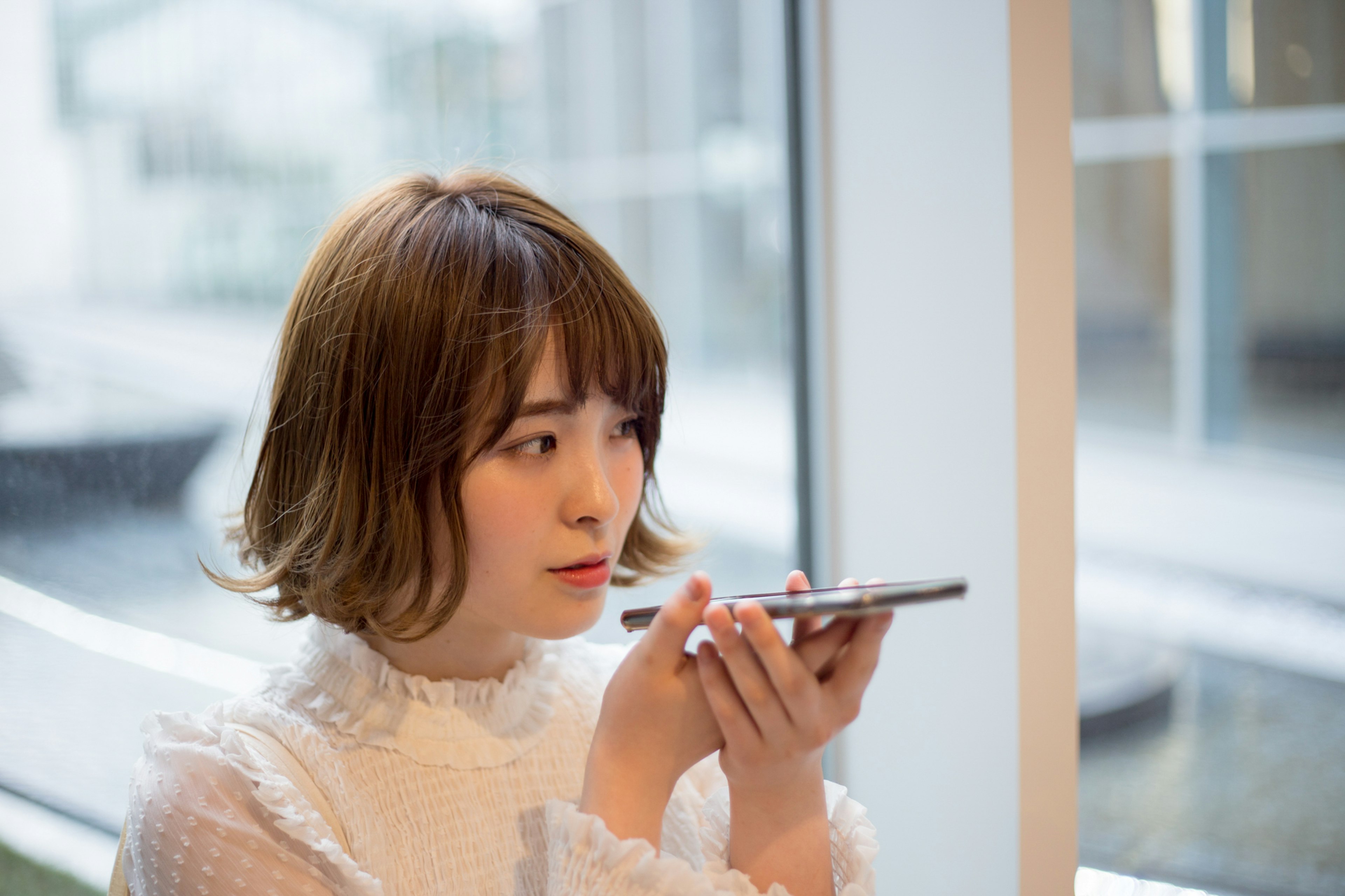 Mujer usando un smartphone junto a la ventana