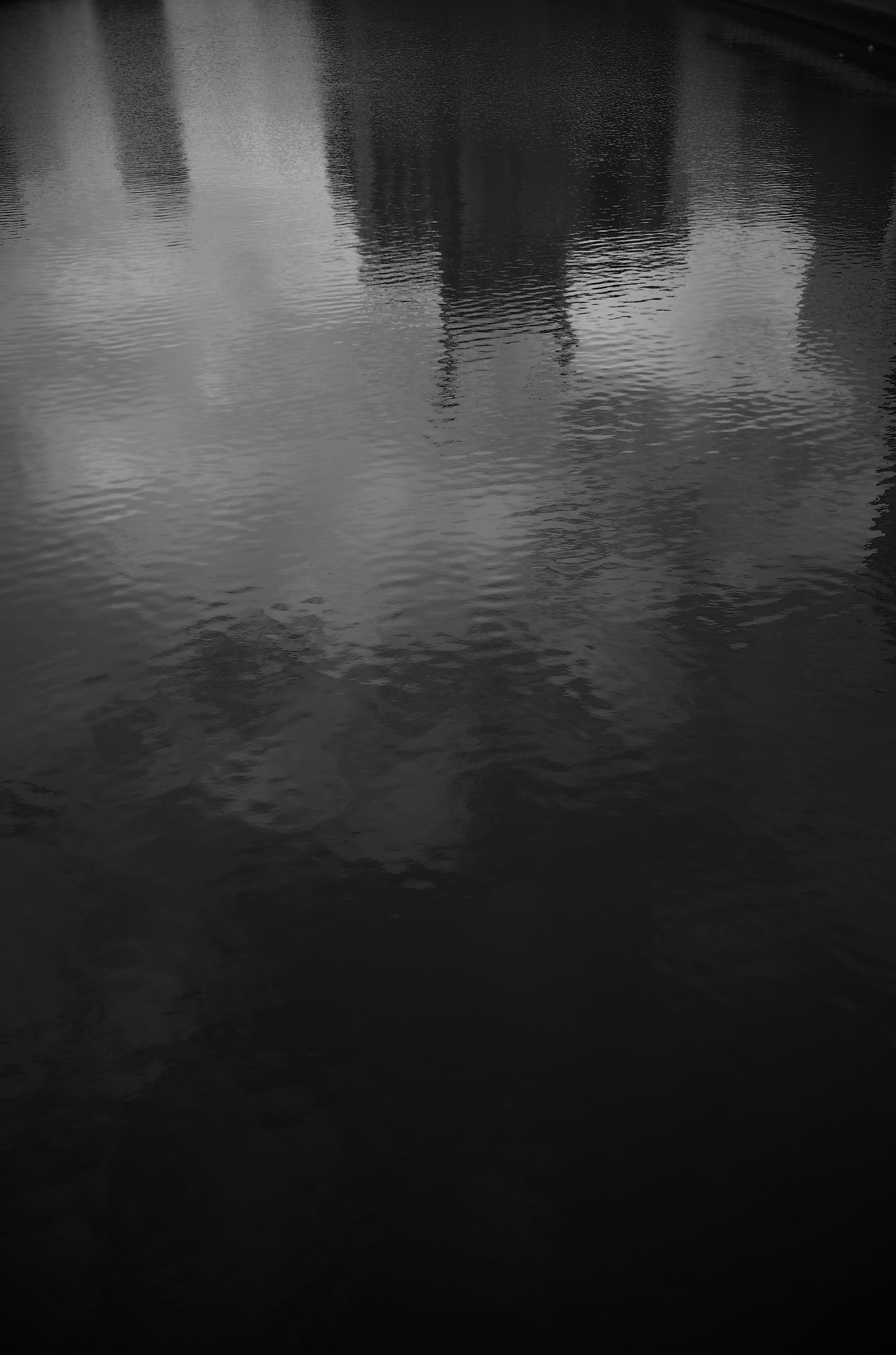 Black and white reflection of clouds and buildings on water surface