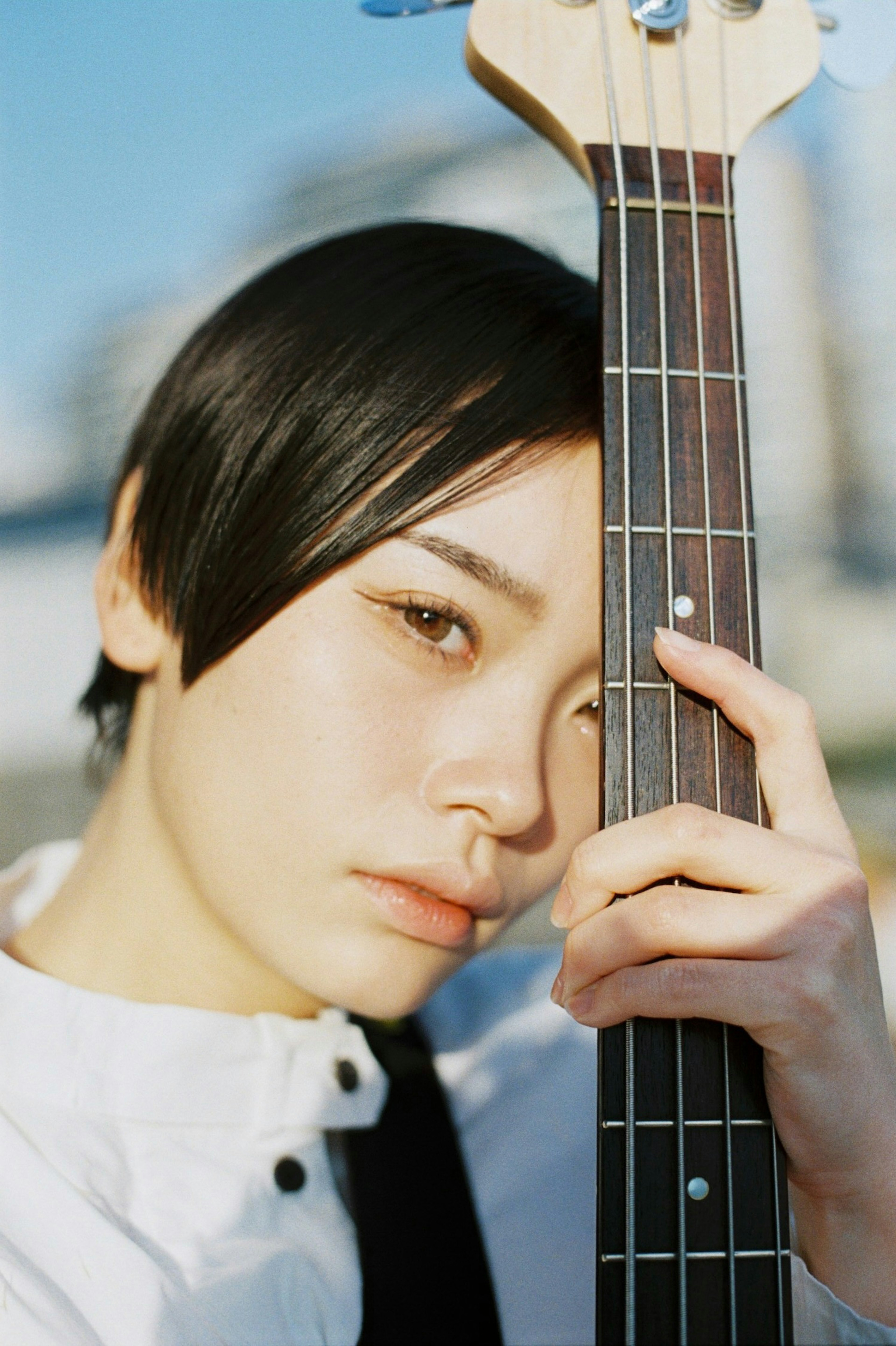 Une jeune femme tenant une basse avec une expression sérieuse regardant la caméra