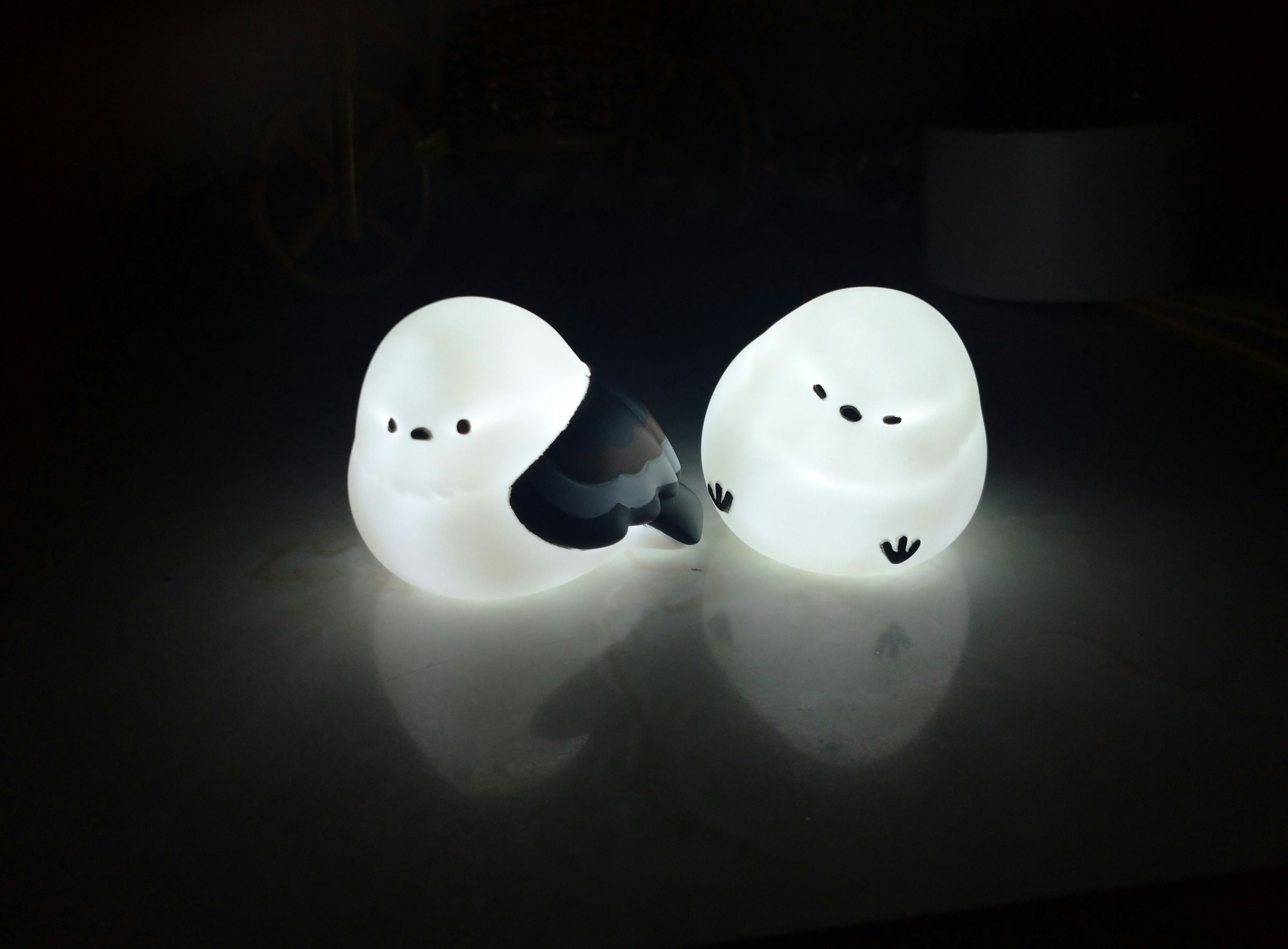 Two cute white snow goose lights glowing against a dark background