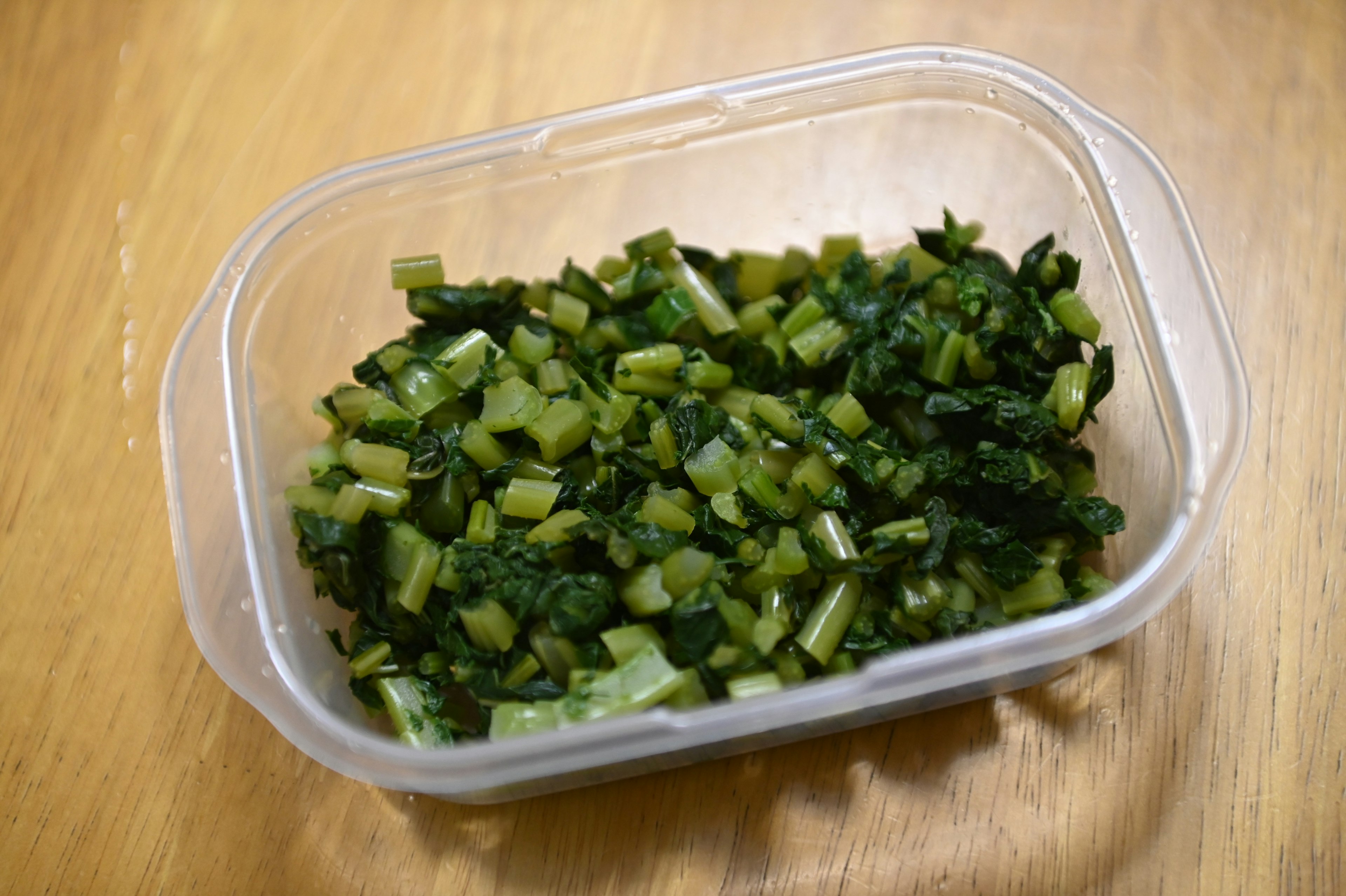 Verduras verdes picadas en un recipiente transparente