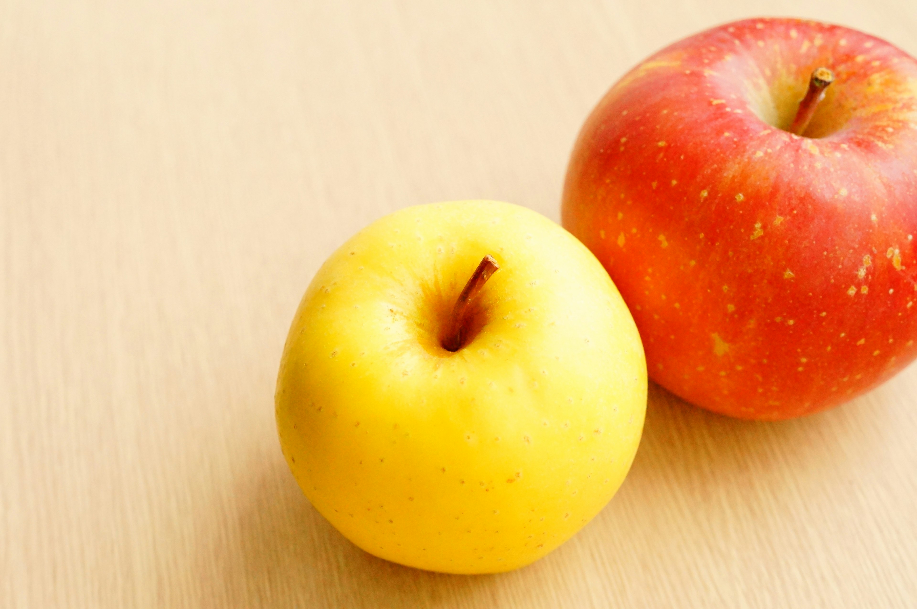 A red apple and a yellow apple on a wooden table