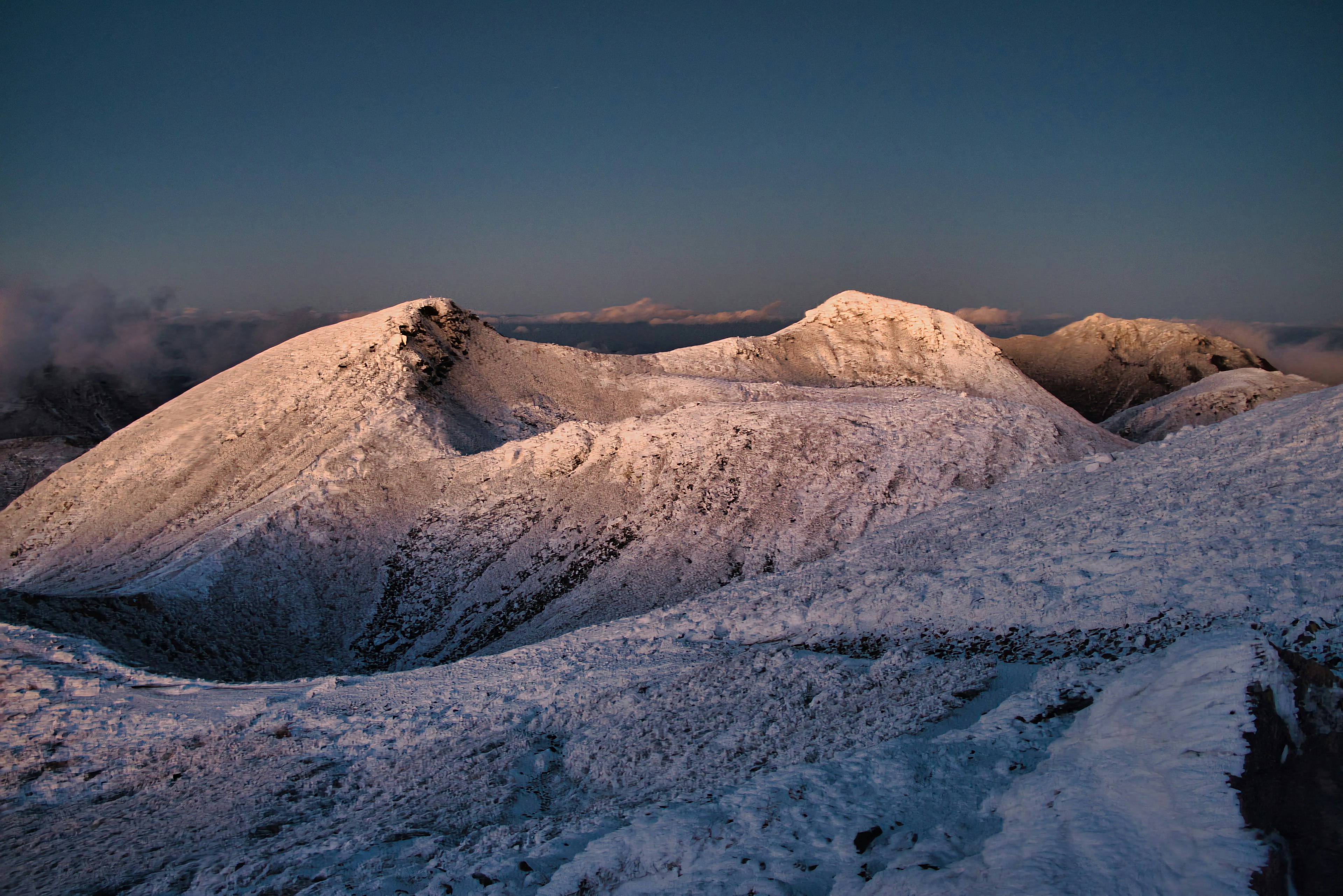 Snow-covered mountain landscape with soft evening light illuminating the peaks