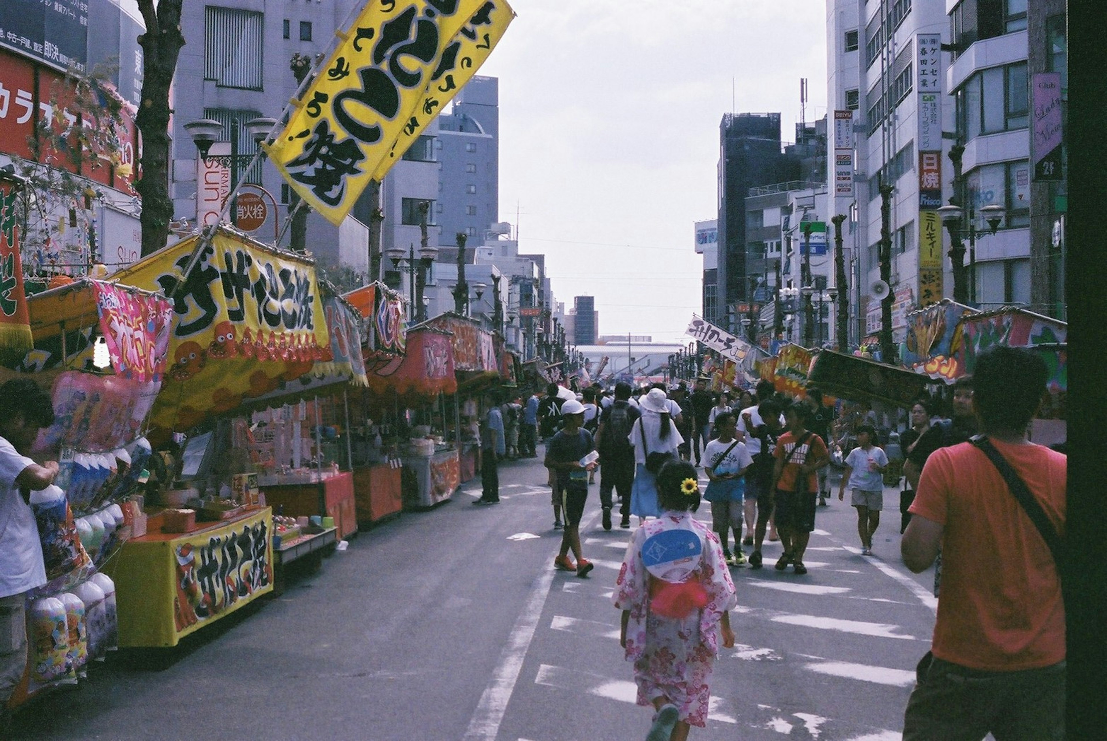 热闹的节日街道，两侧是美食摊位和人群