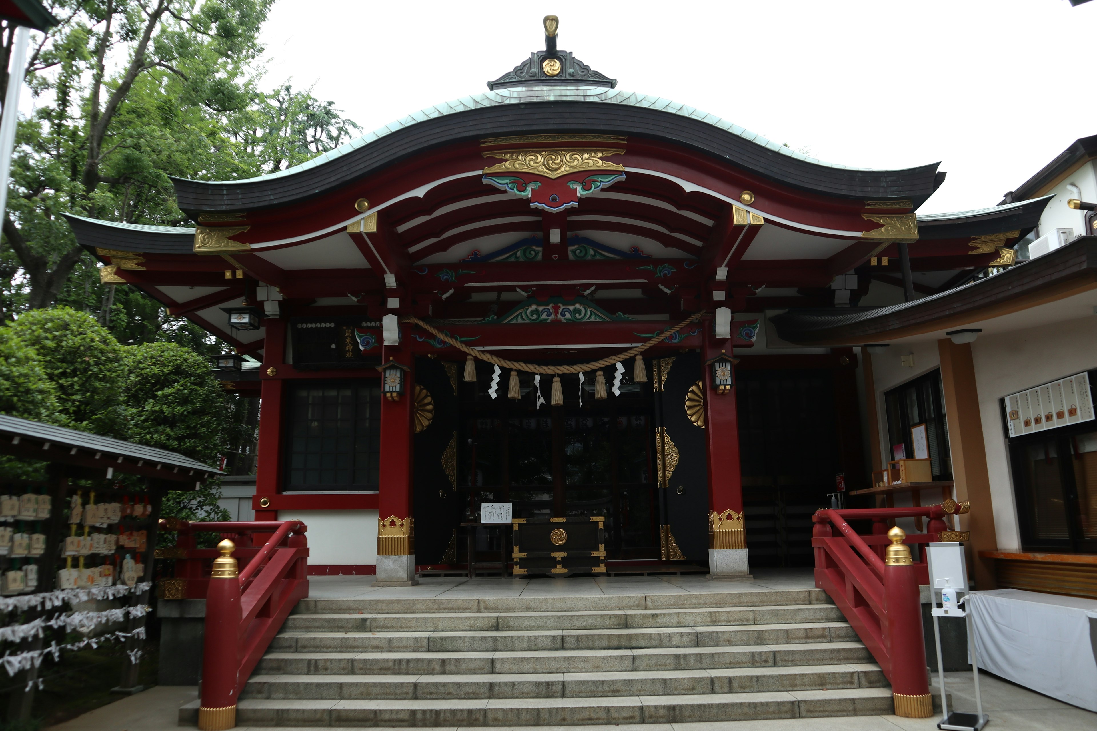 Entrance of a beautiful shrine with a red roof featuring decorative pillars and stairs