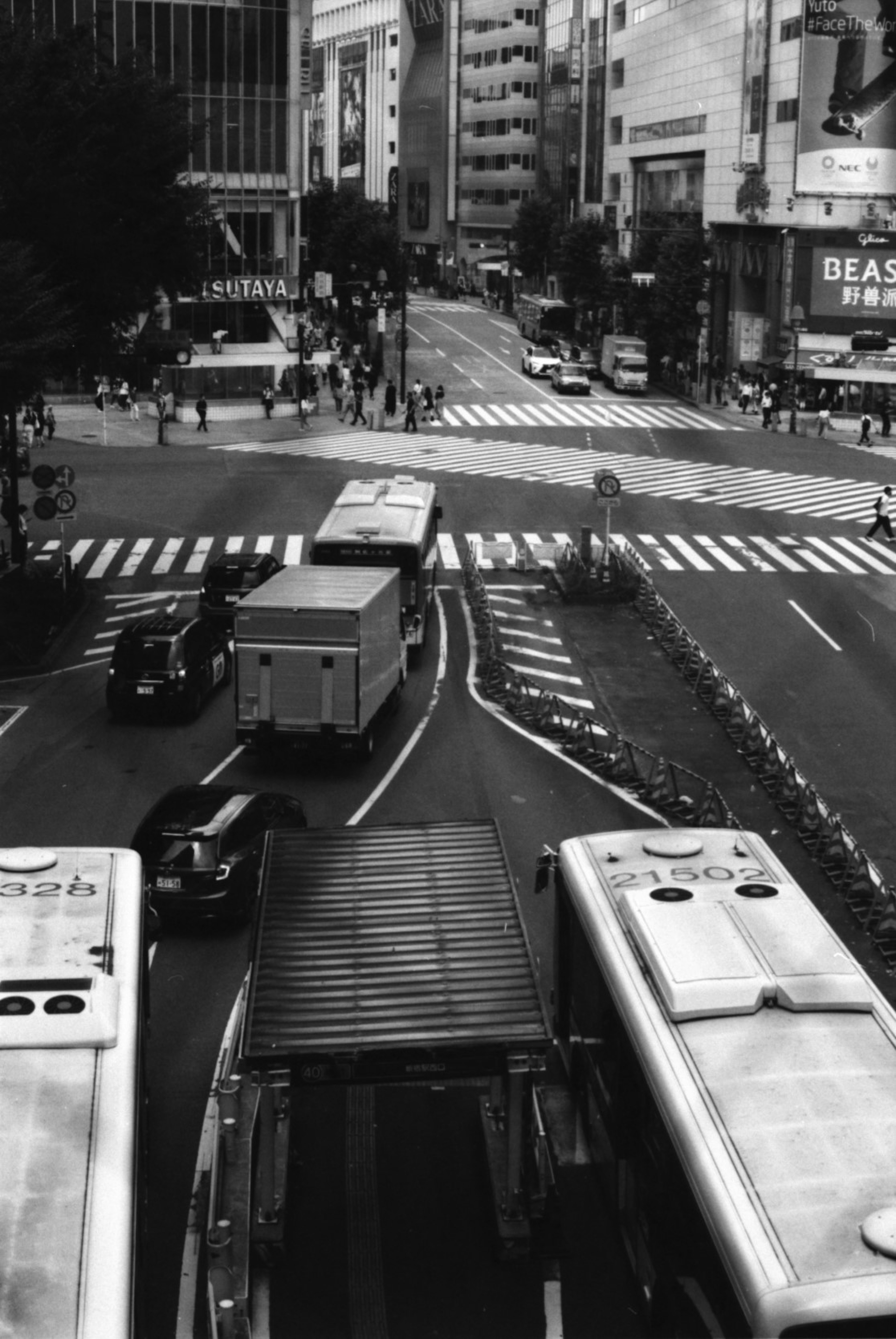 繁華街の交差点に集まるバスとトラックの交通風景