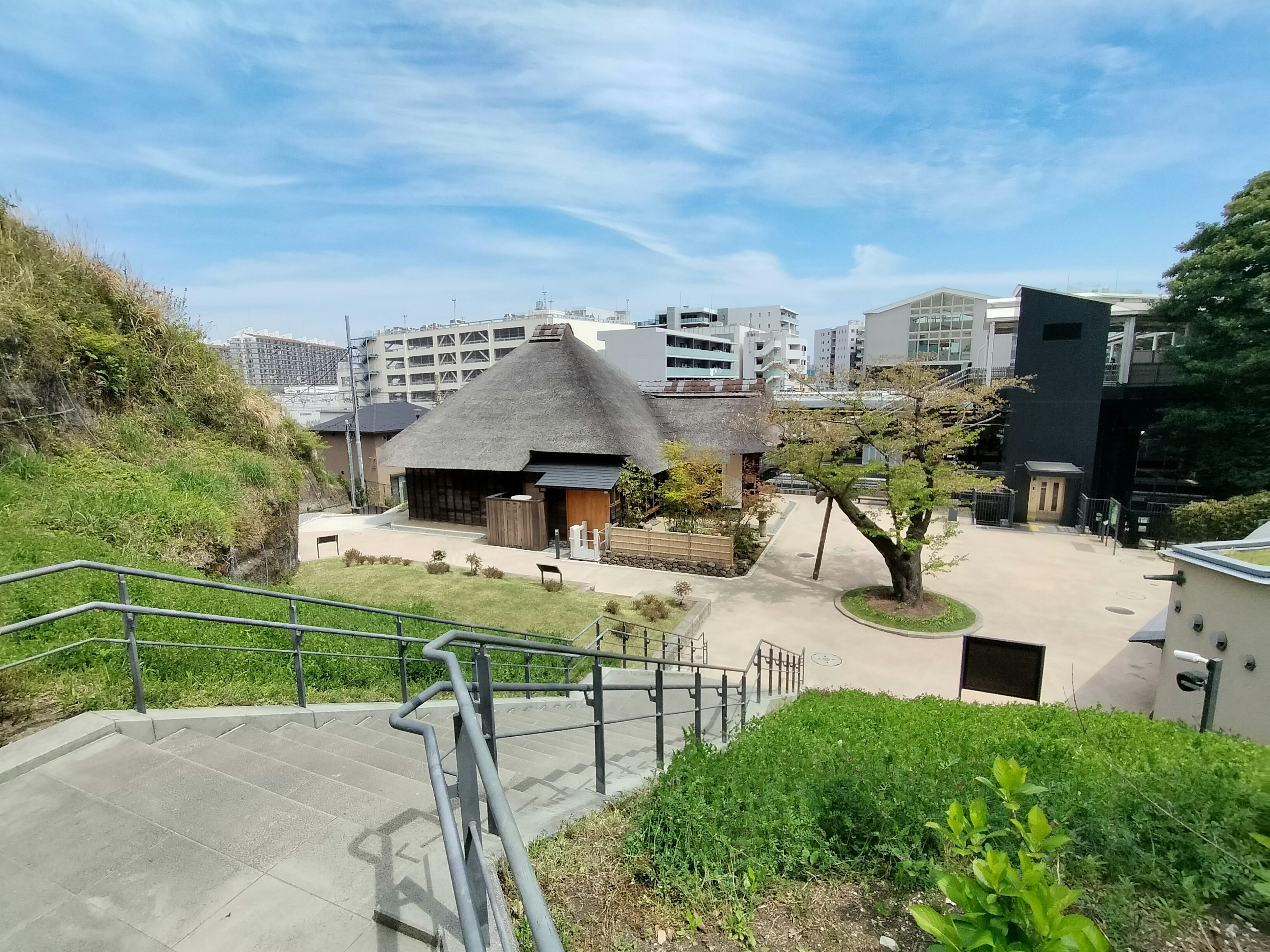 現代的な建物と伝統的な茅葺き屋根の家が共存する風景