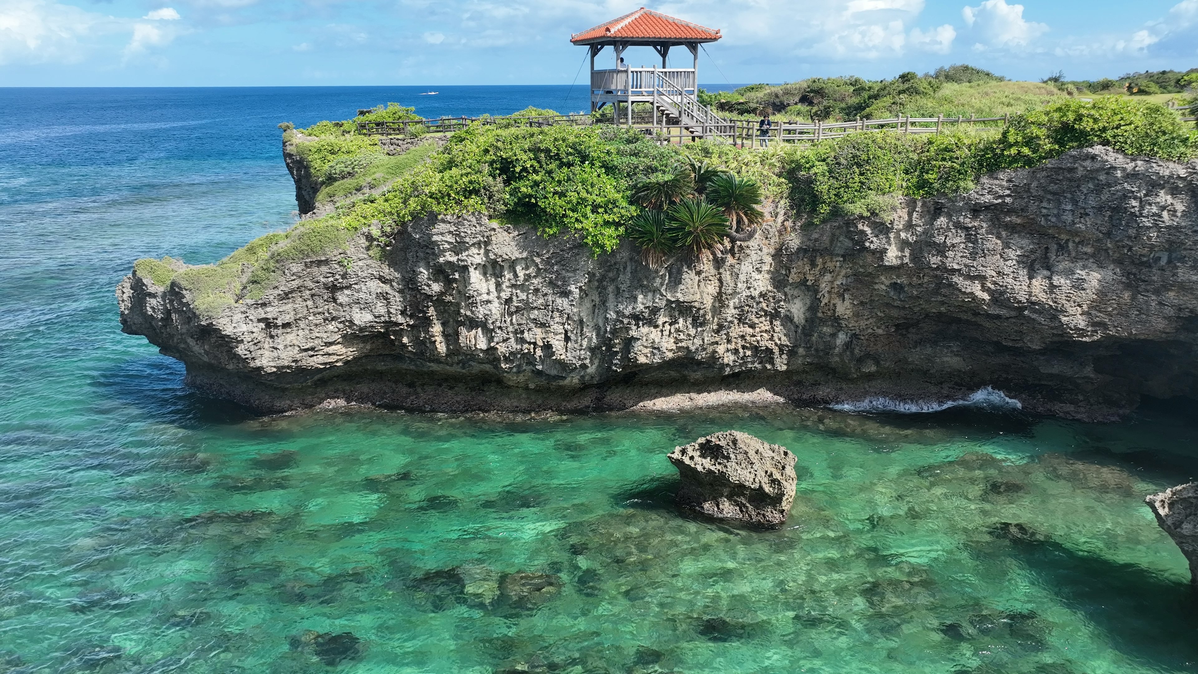 Scenic view of a rocky cliff with a gazebo by the turquoise sea