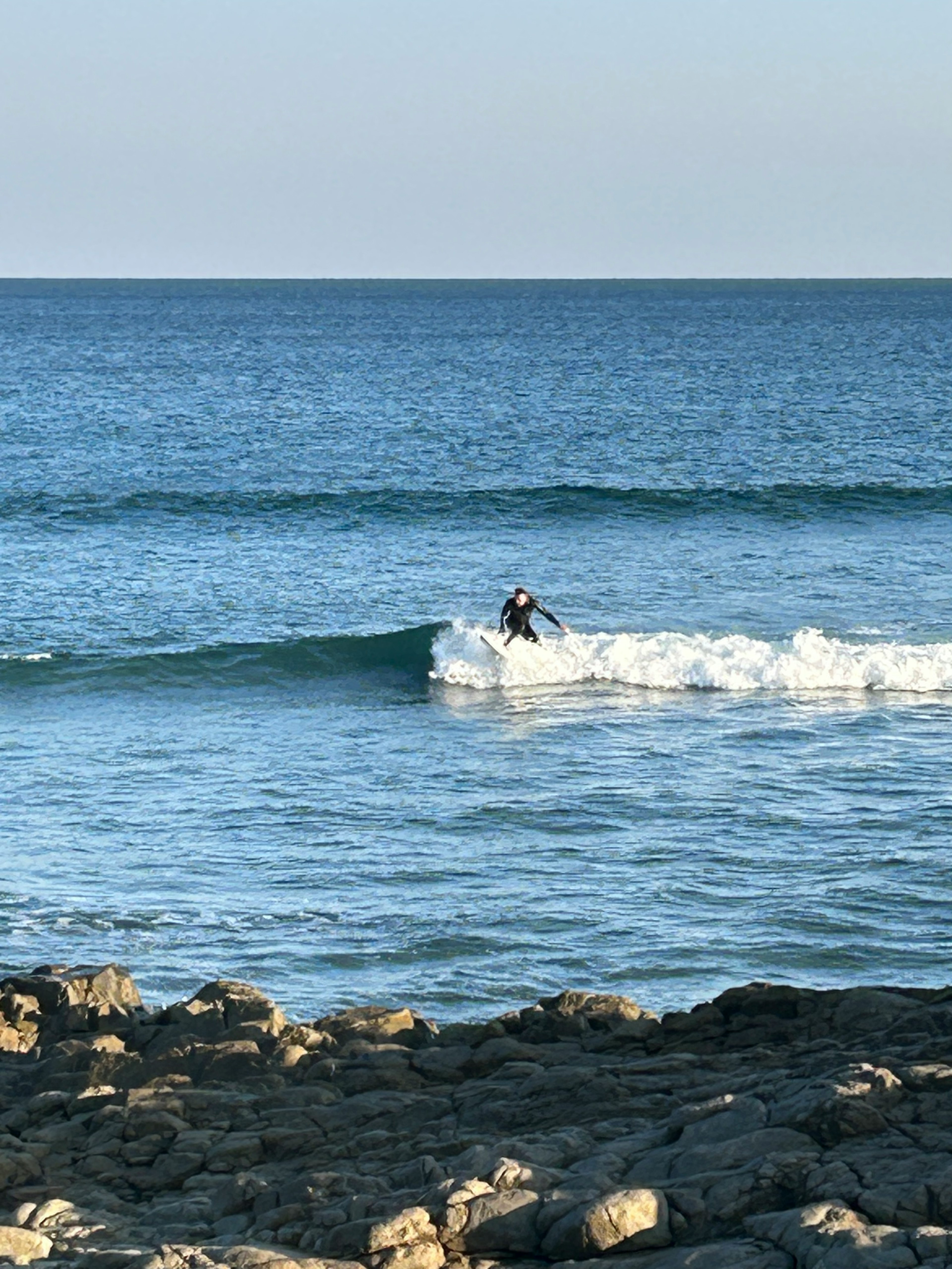 Una persona che fa surf su un'onda nell'oceano con una costa rocciosa