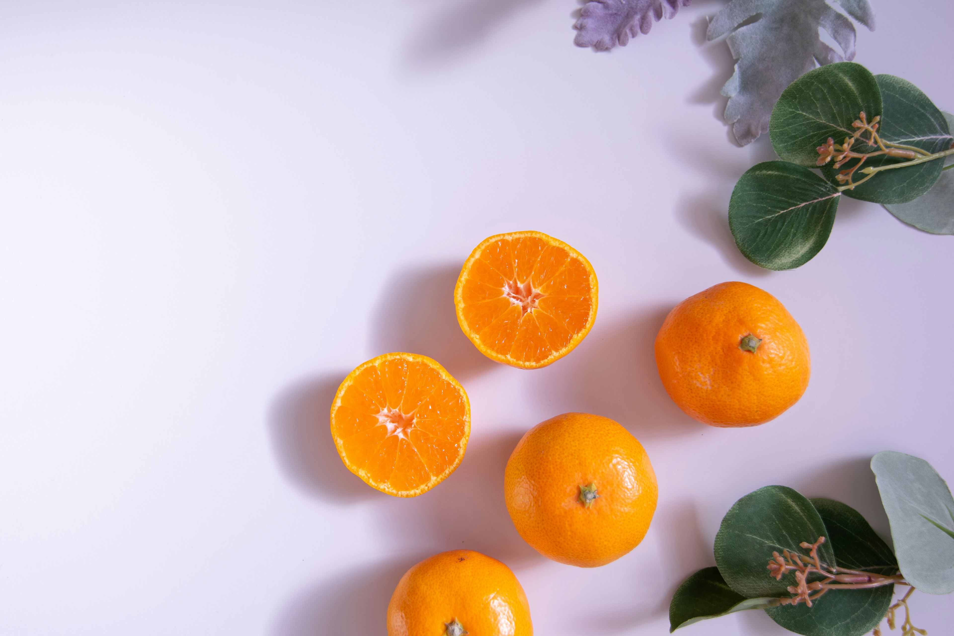 Naturaleza muerta de naranjas con hojas mostrando naranjas enteras y cortadas