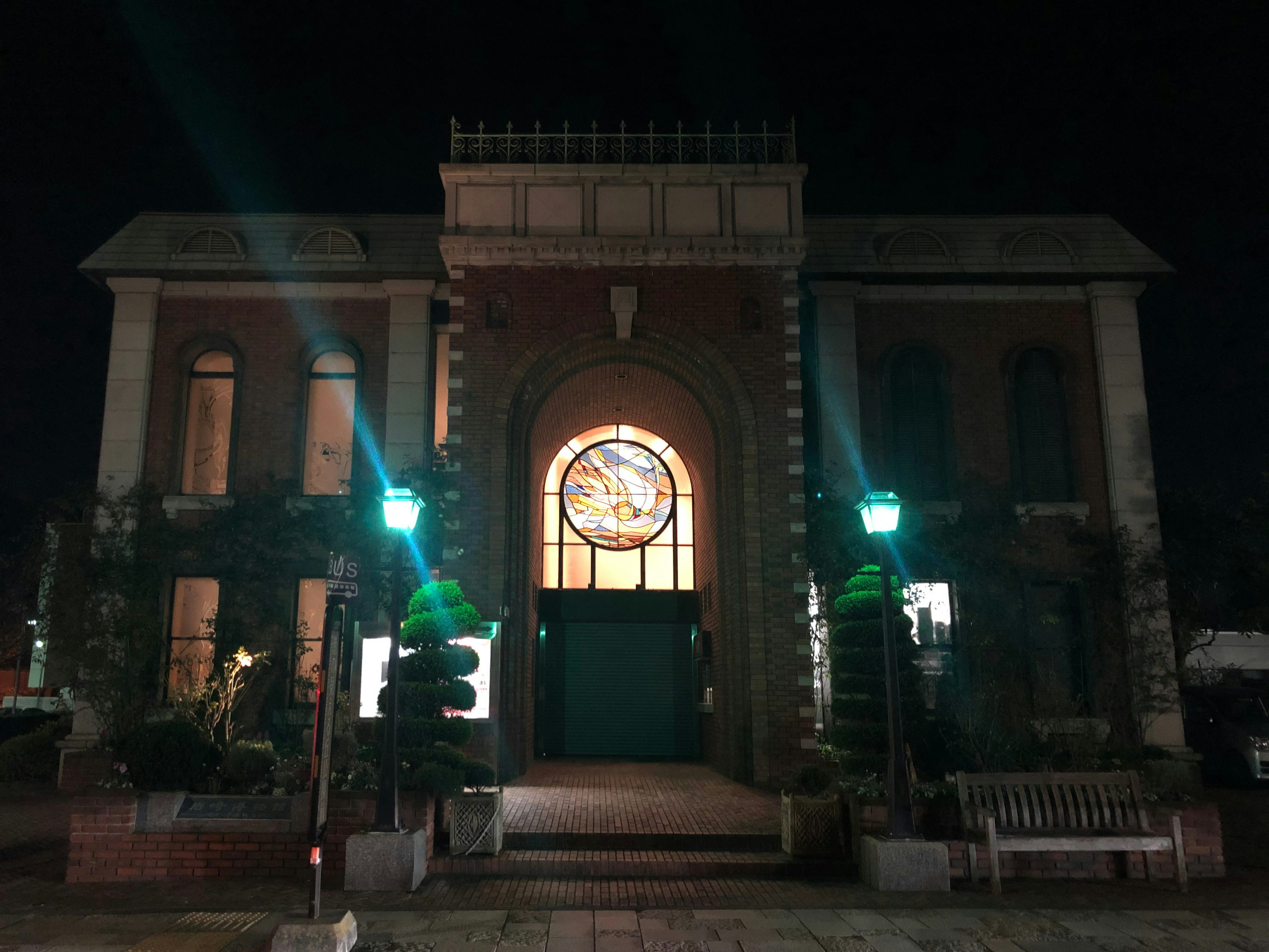 Edificio histórico iluminado por la noche con arquitectura decorativa y vegetación circundante