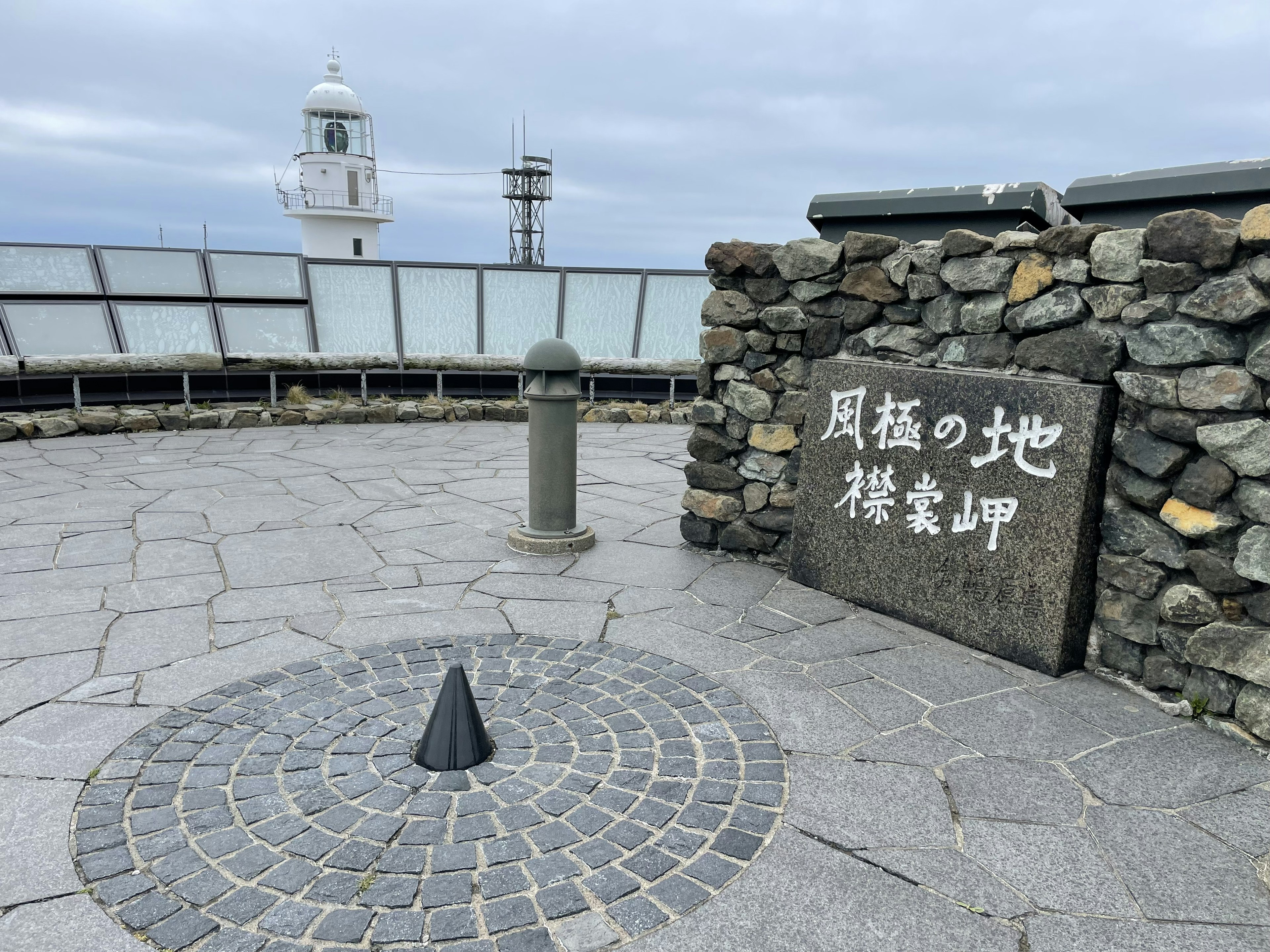 Monumento de piedra con un cono negro sobre un pavimento de piedra