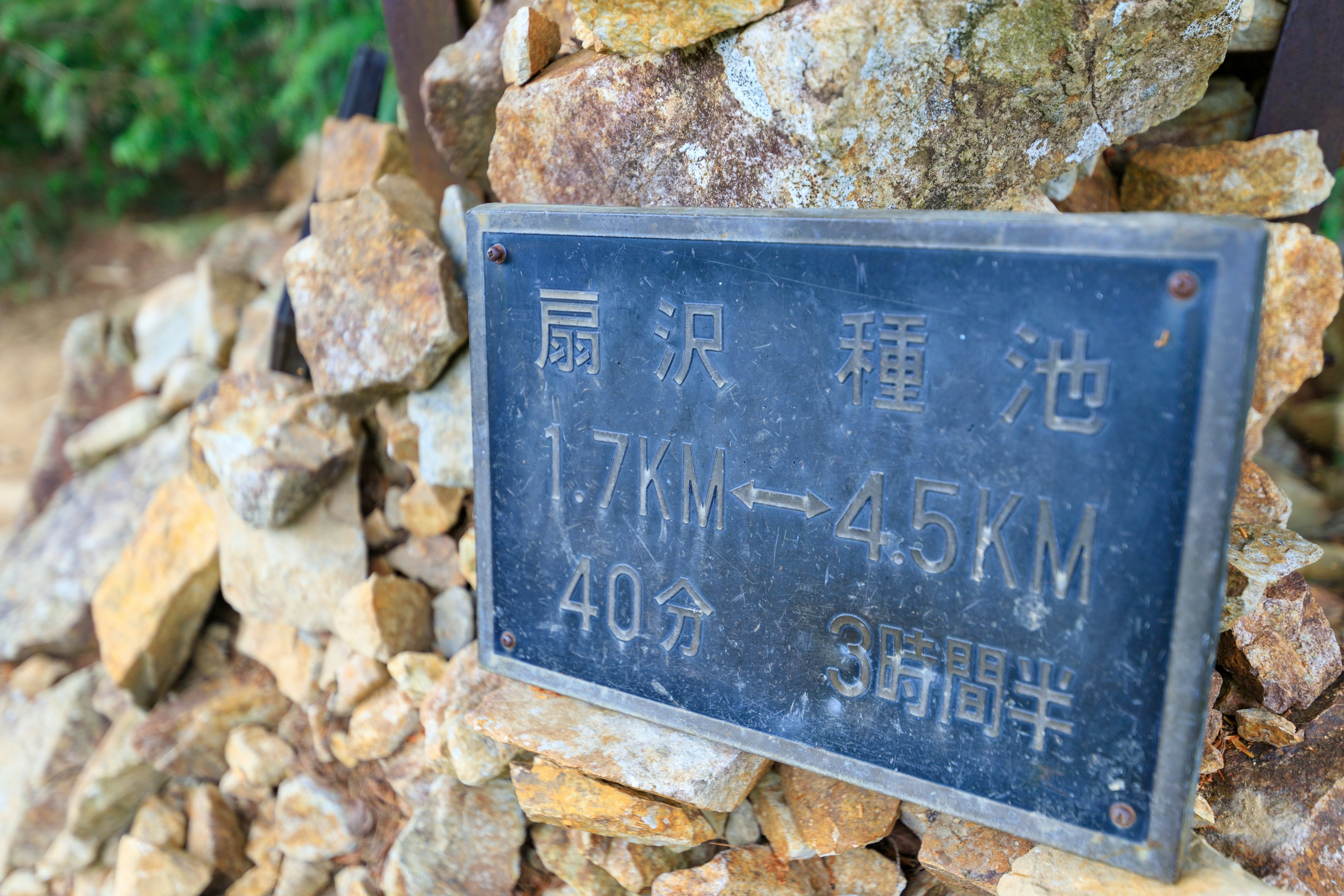 Panneau sur un tas de pierres indiquant des distances de 1,7 KM à 45 KM et des temps de 40 minutes et 35 minutes