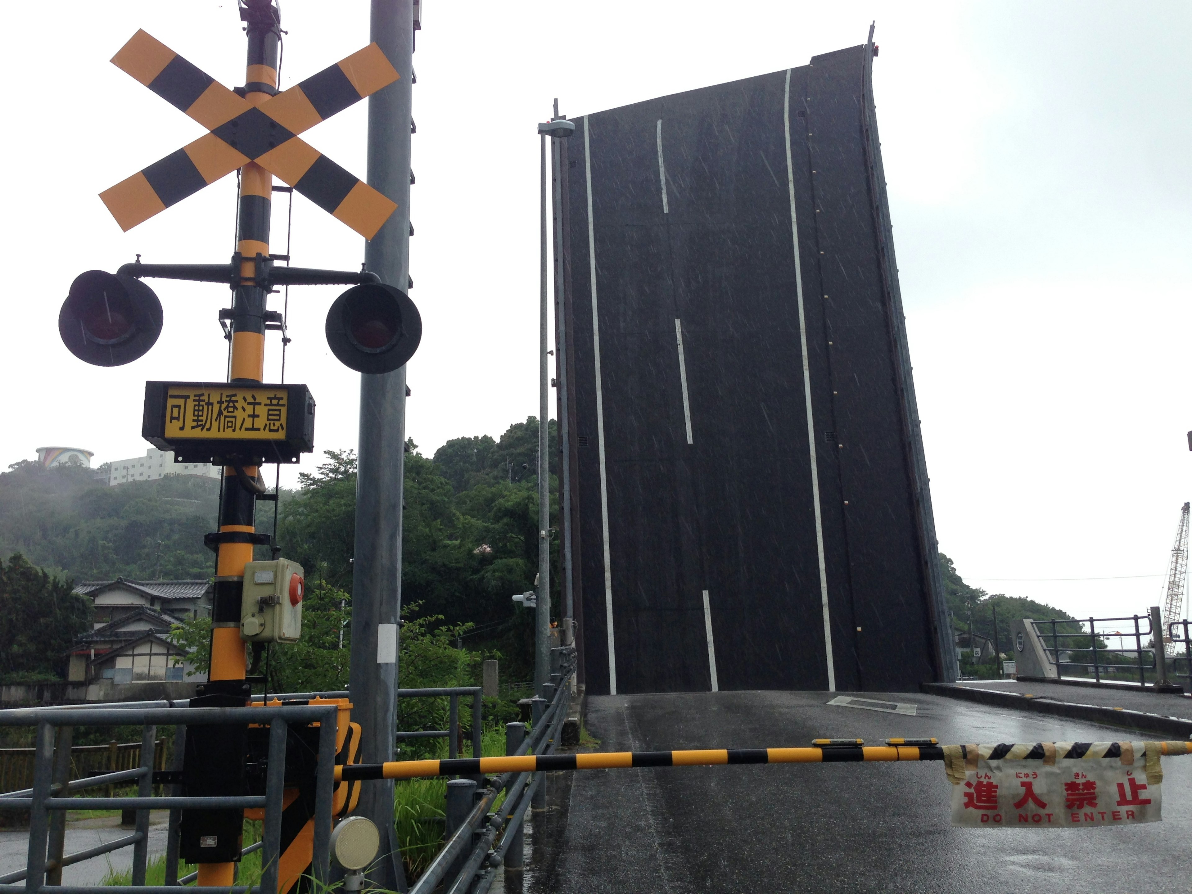 A railway crossing with a raised drawbridge and warning signals