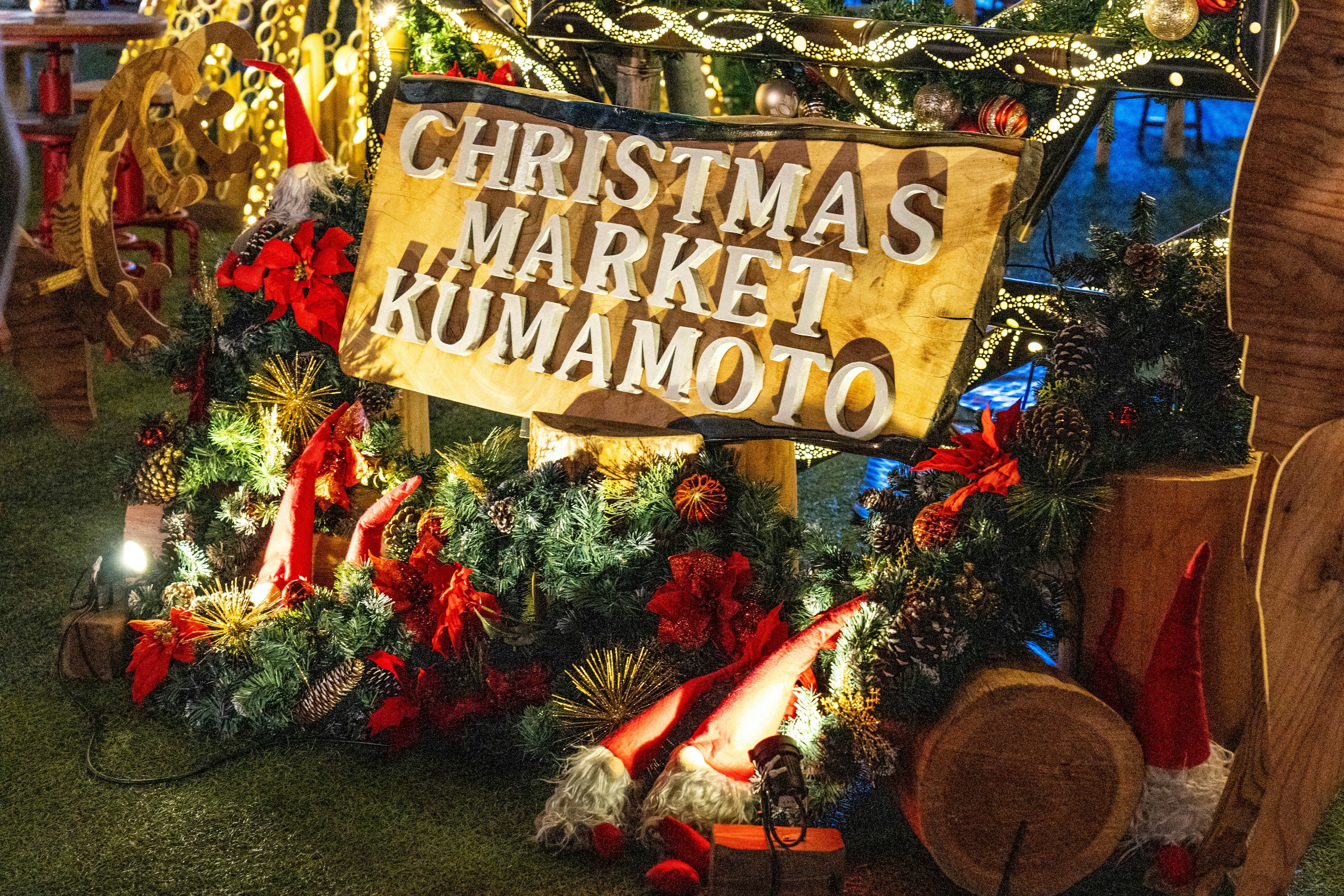 Schild für den Weihnachtsmarkt Kumamoto umgeben von festlichen Dekorationen