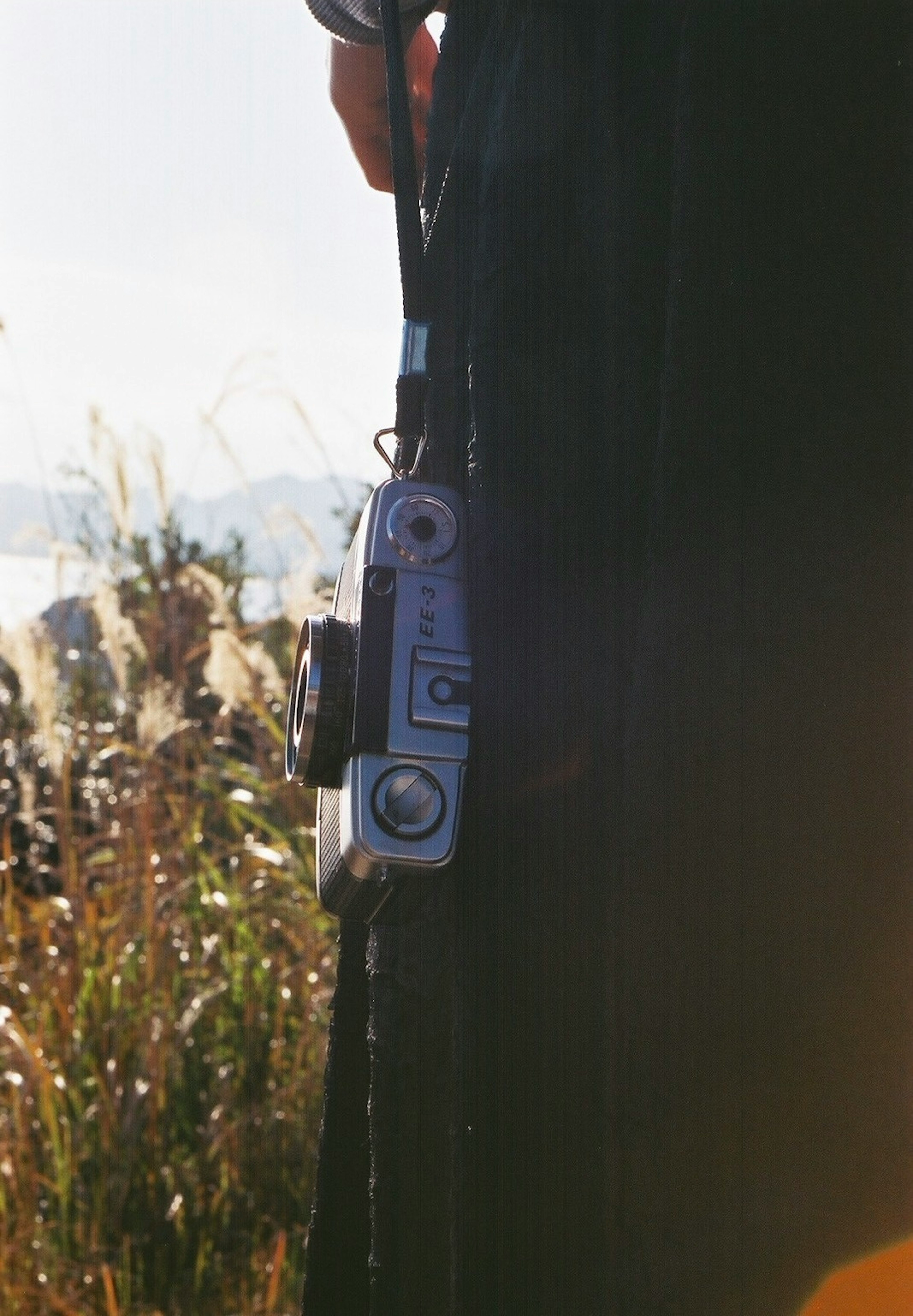 Side view of a person holding a camera with natural scenery in the background