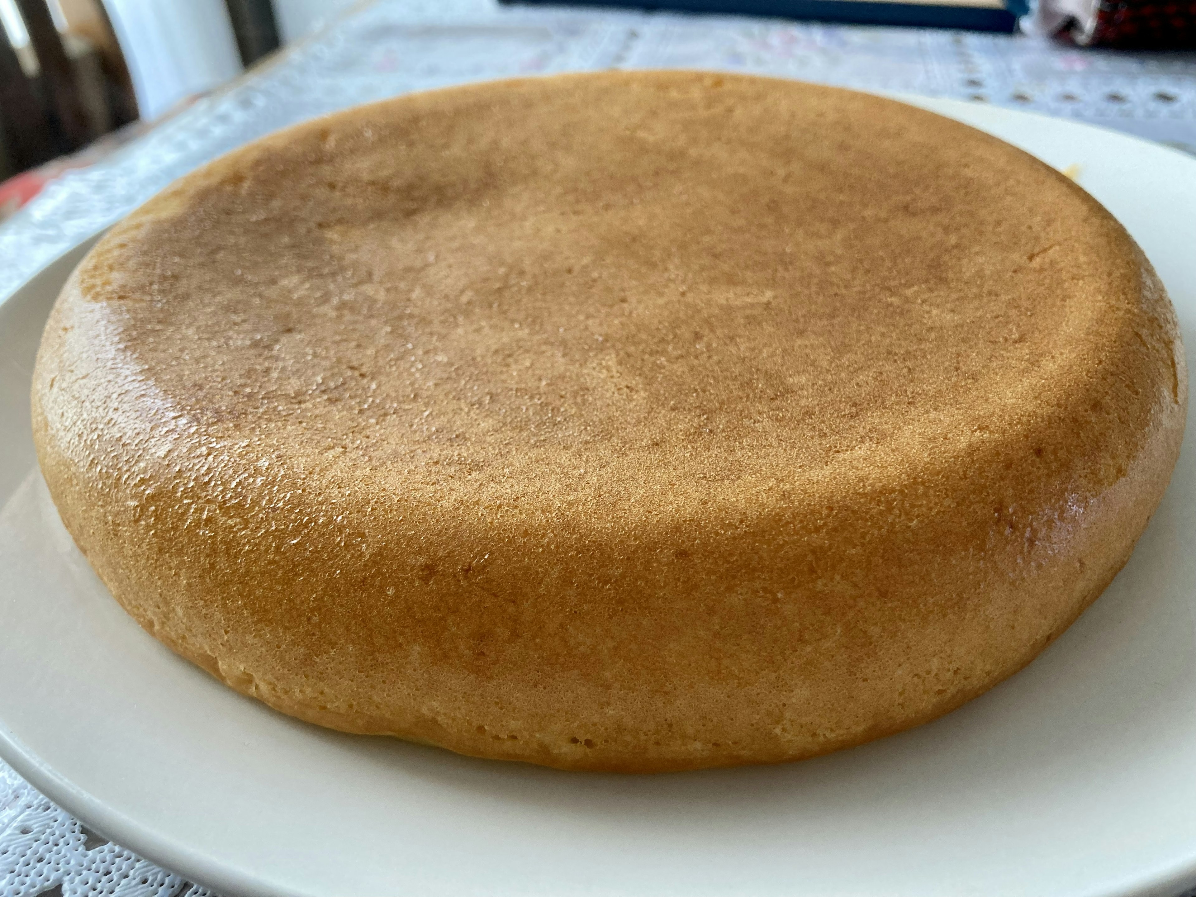 A flat and glossy brown cake on a white plate