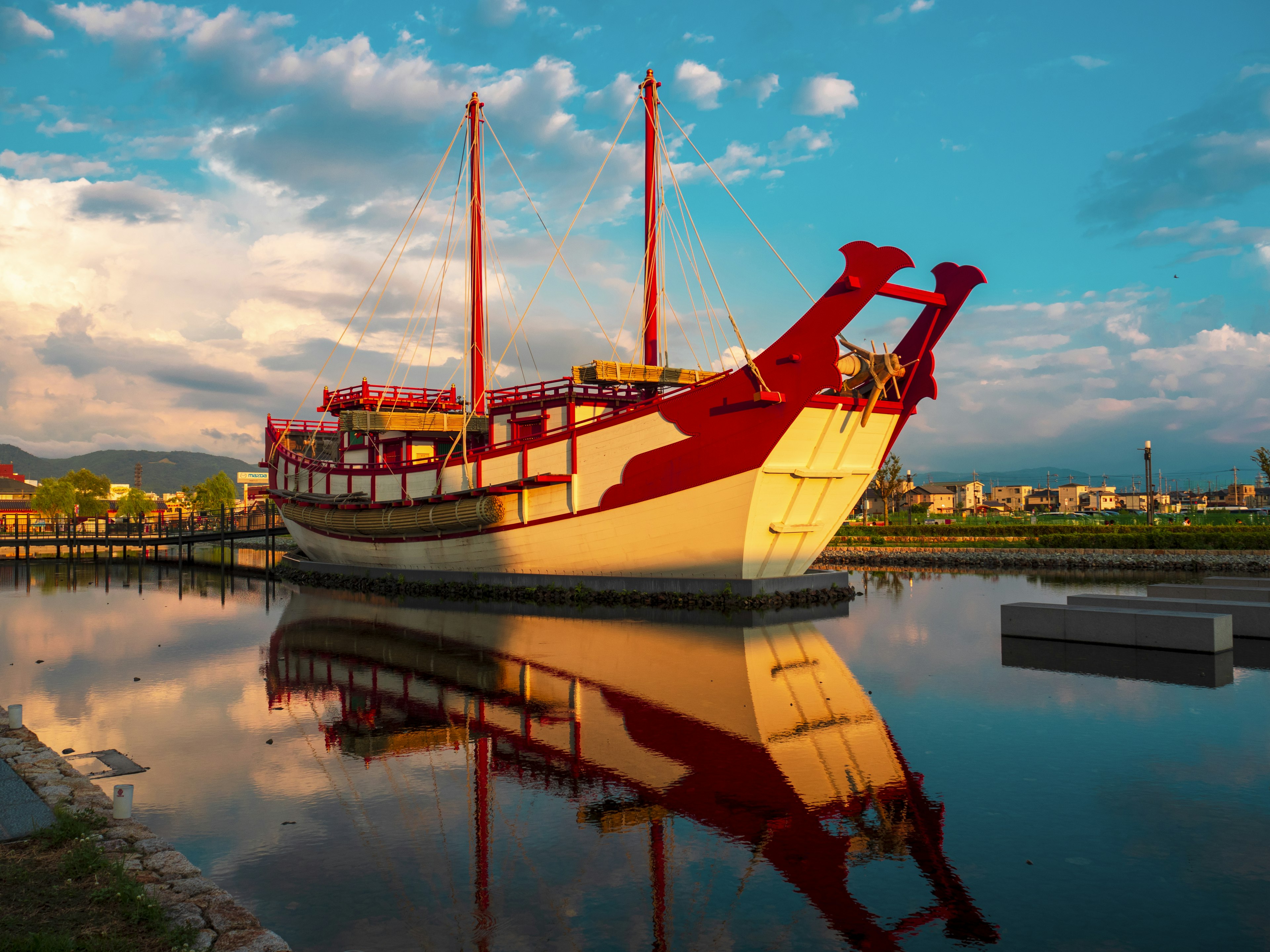 Barco tradicional rojo y blanco reflejándose en agua tranquila en un paisaje pintoresco