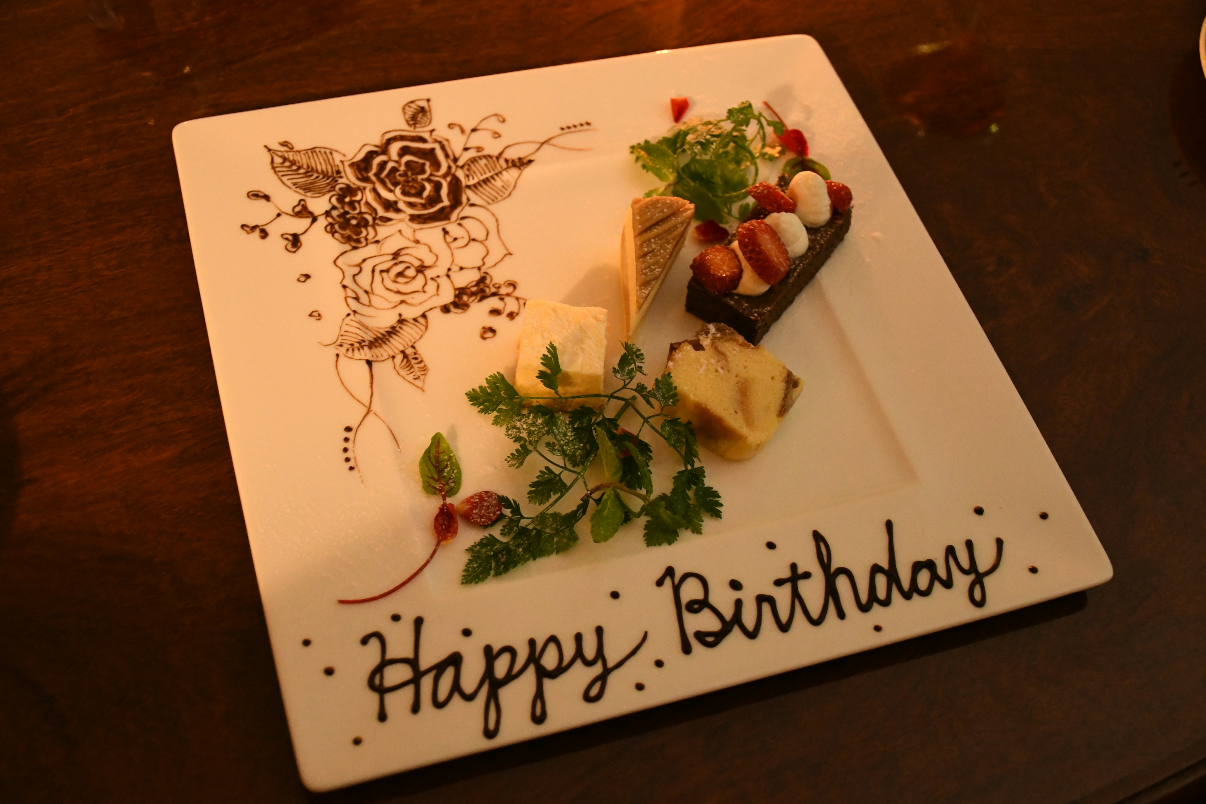 Dessert plate featuring birthday greeting with decorative elements and fresh ingredients