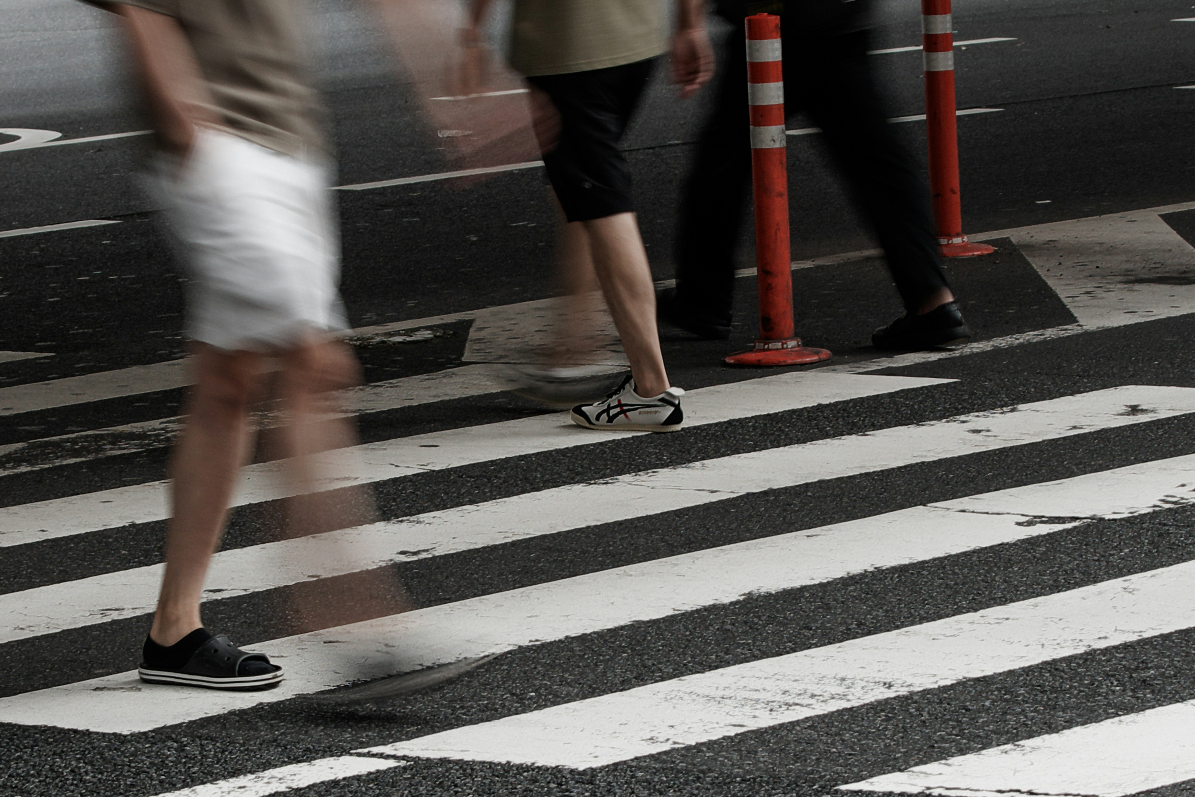 Menschen gehen über einen Zebrastreifen in Shorts und Turnschuhen