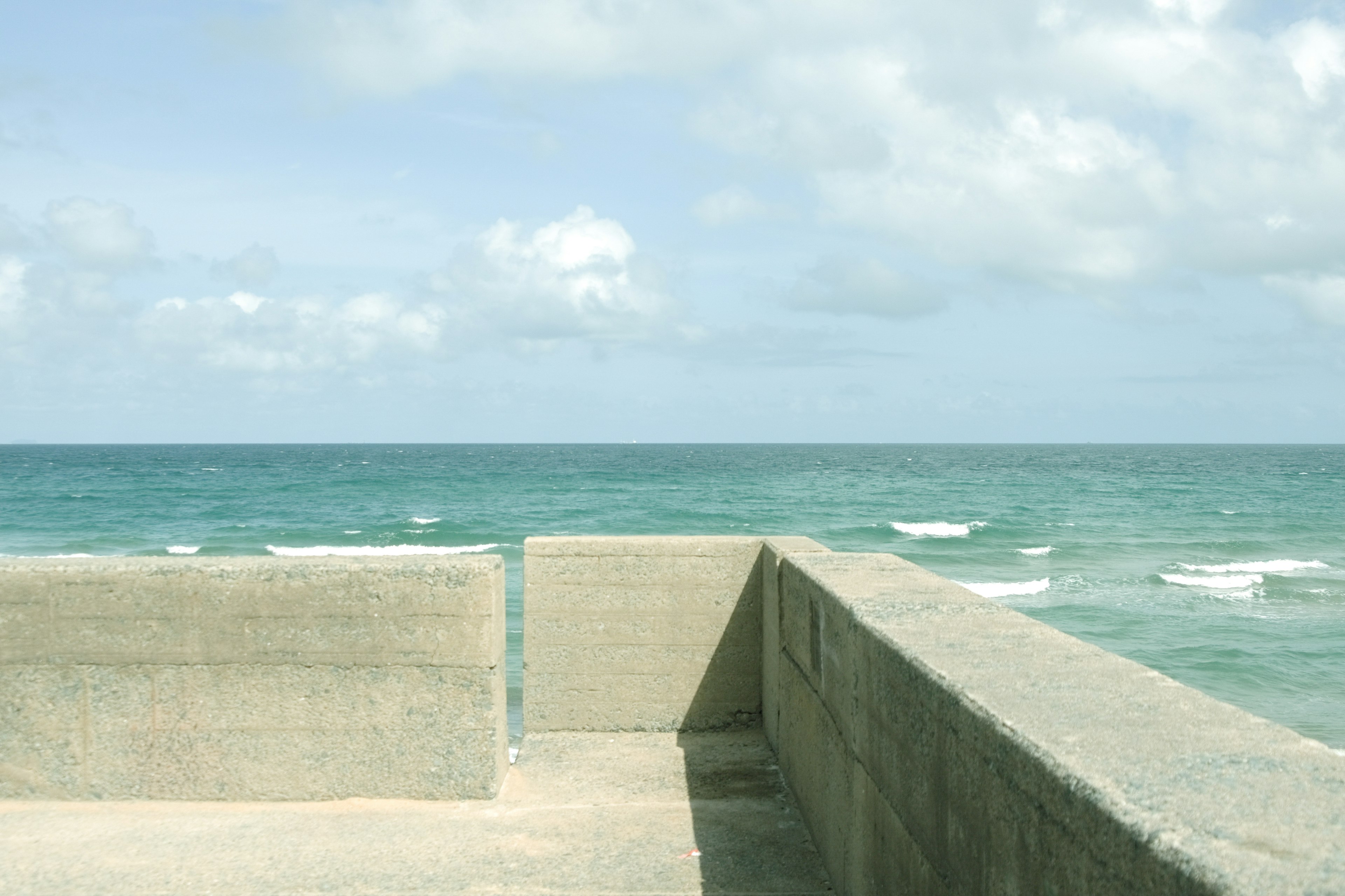 Betonwand zum Ozean mit sanften Wellen