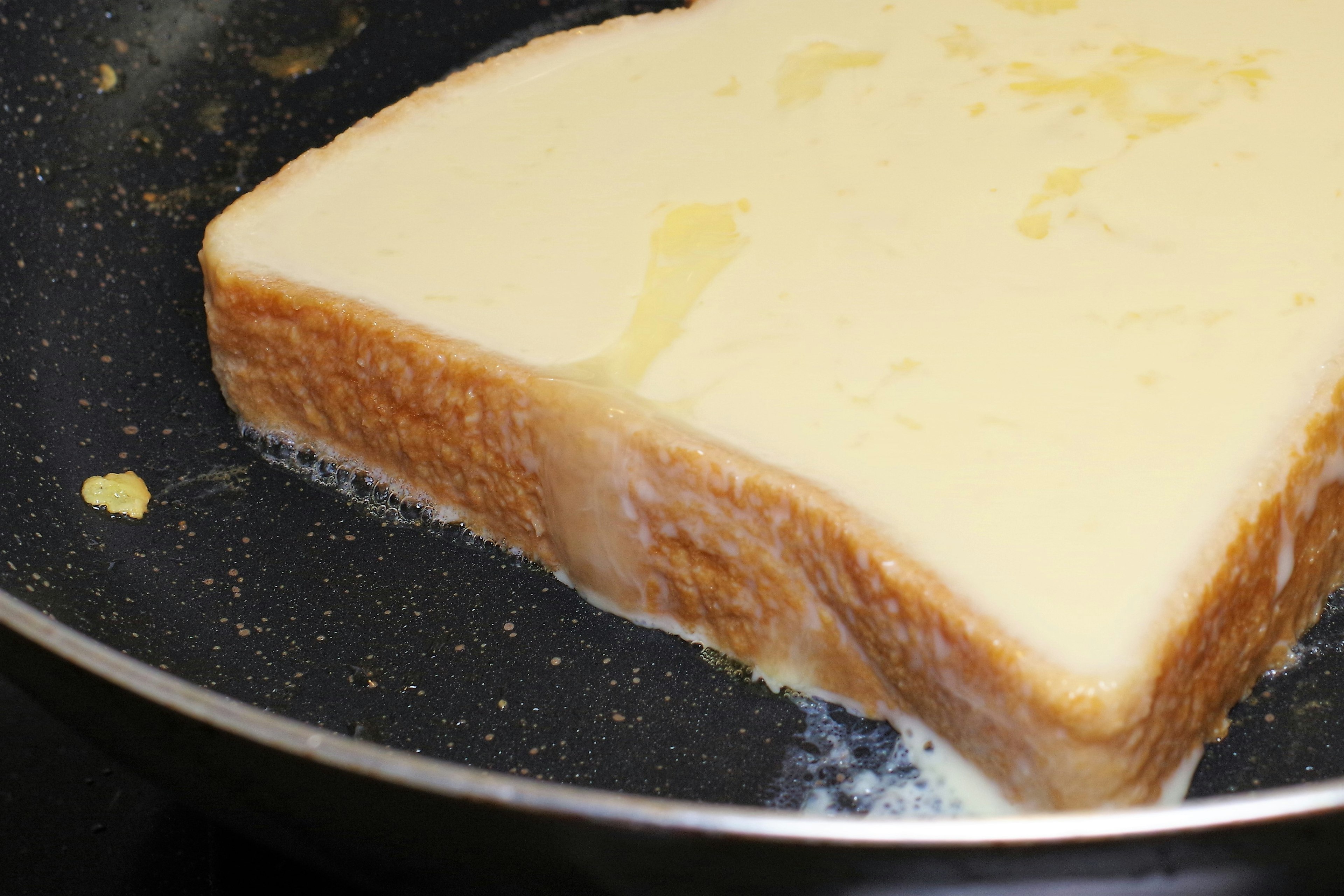 Thick slice of bread being cooked in a frying pan