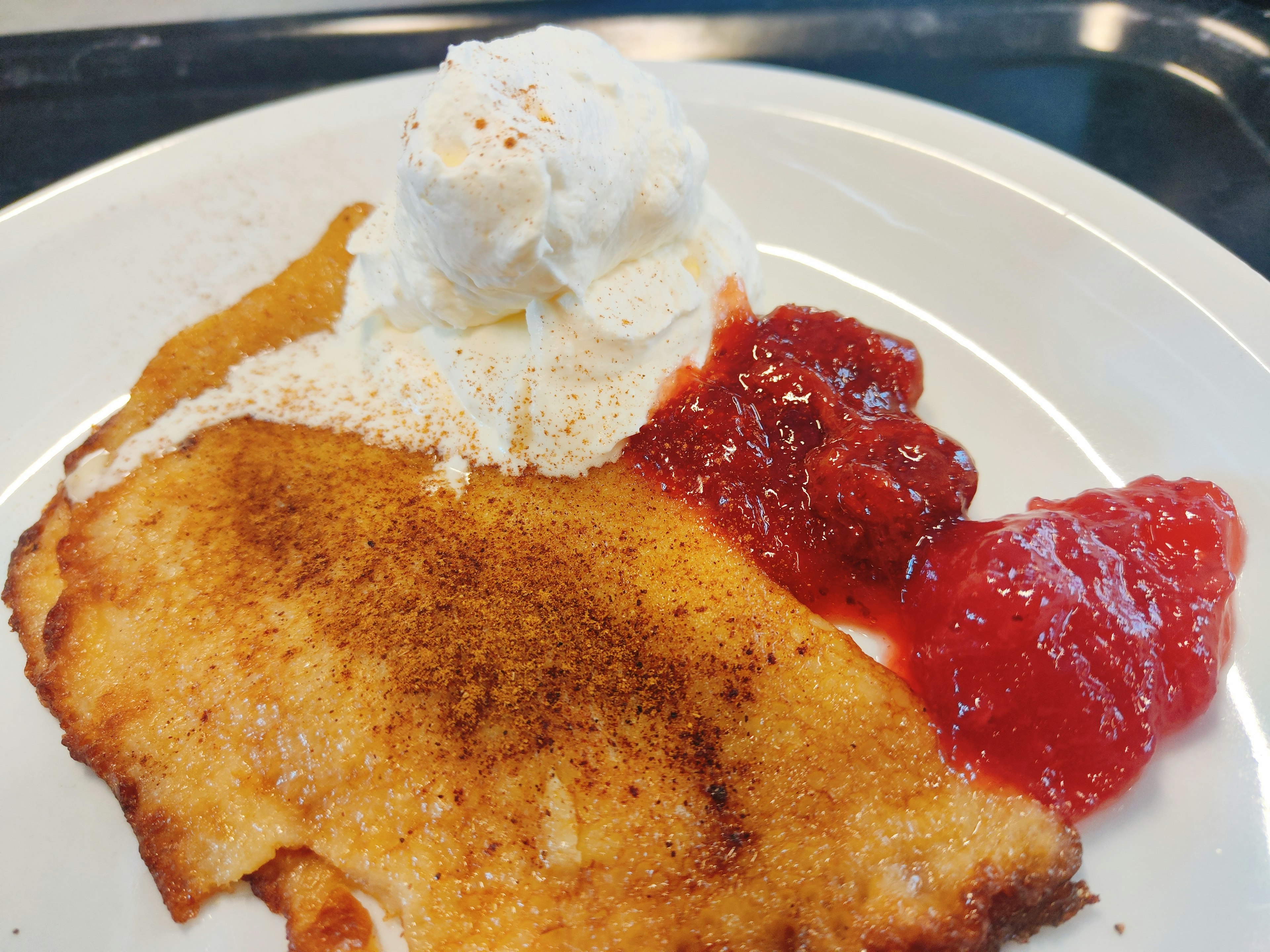 Un piatto di dessert dolce guarnito con crema e salsa di fragole